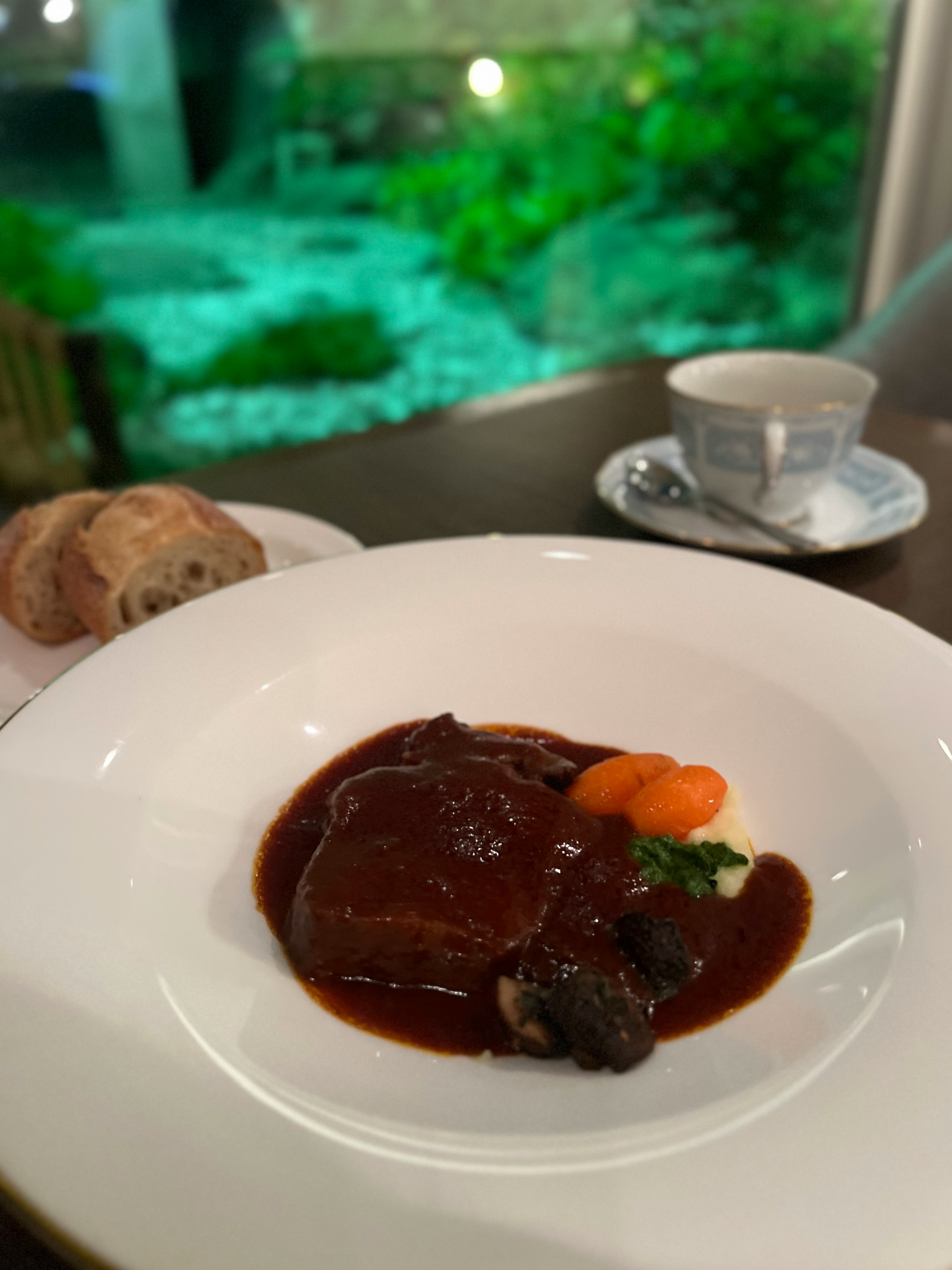 Plato elegante con carne en salsa y guarnición de verduras en un entorno de alta cocina