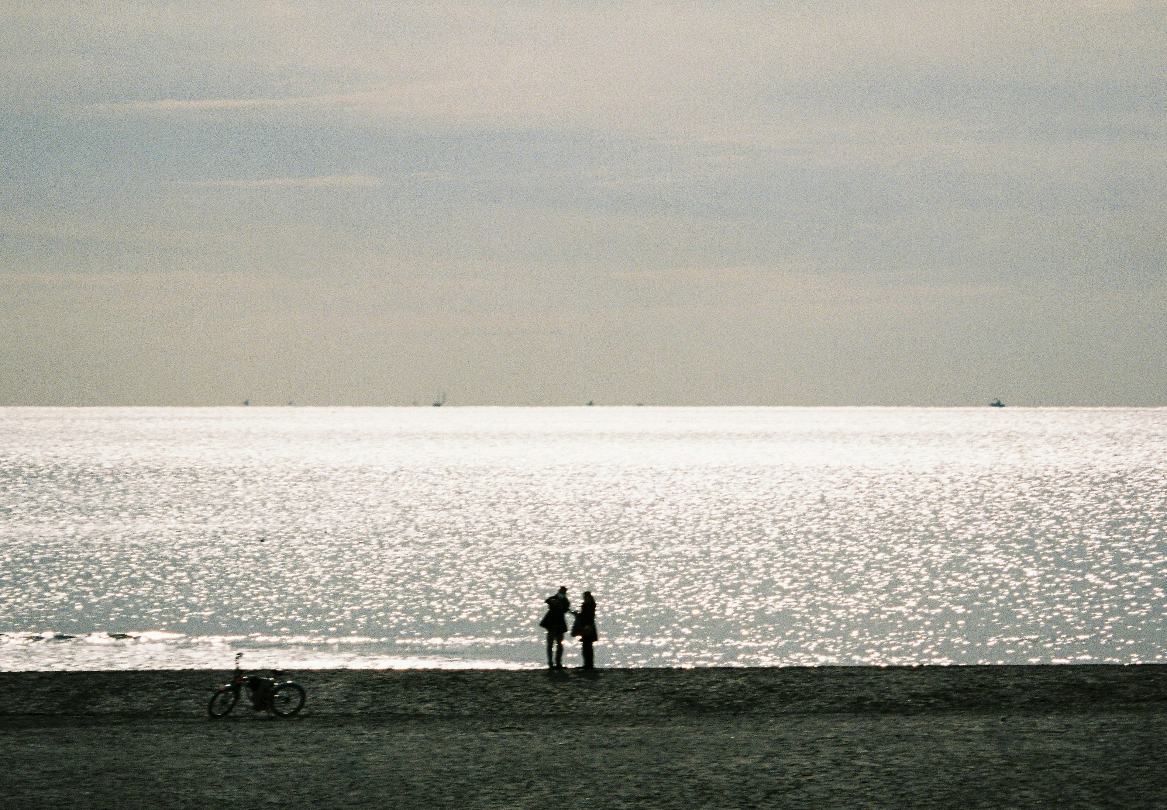 Couple standing on a quiet beach looking at the sea