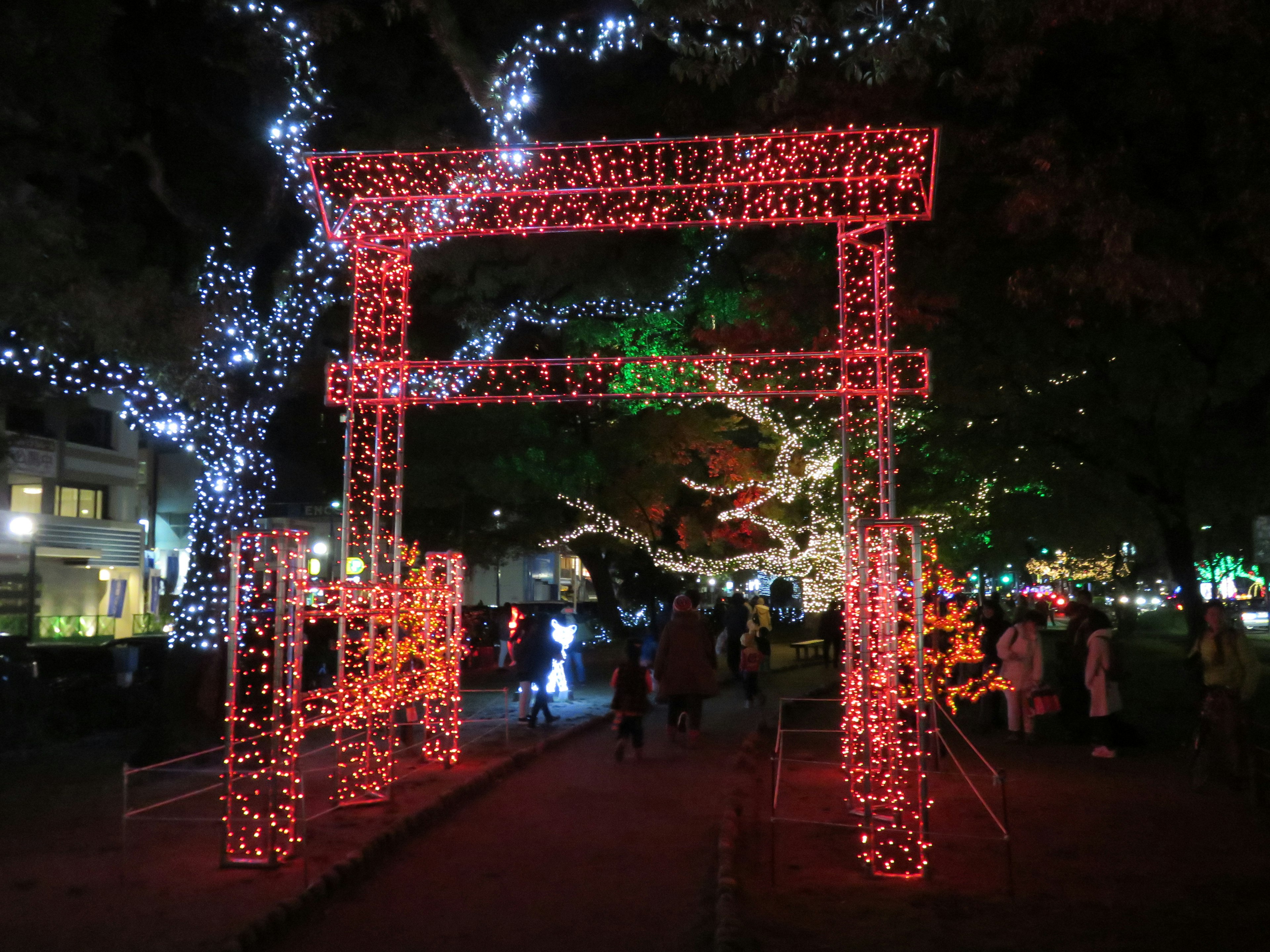 夜にライトアップされた赤い鳥居と周囲のイルミネーション