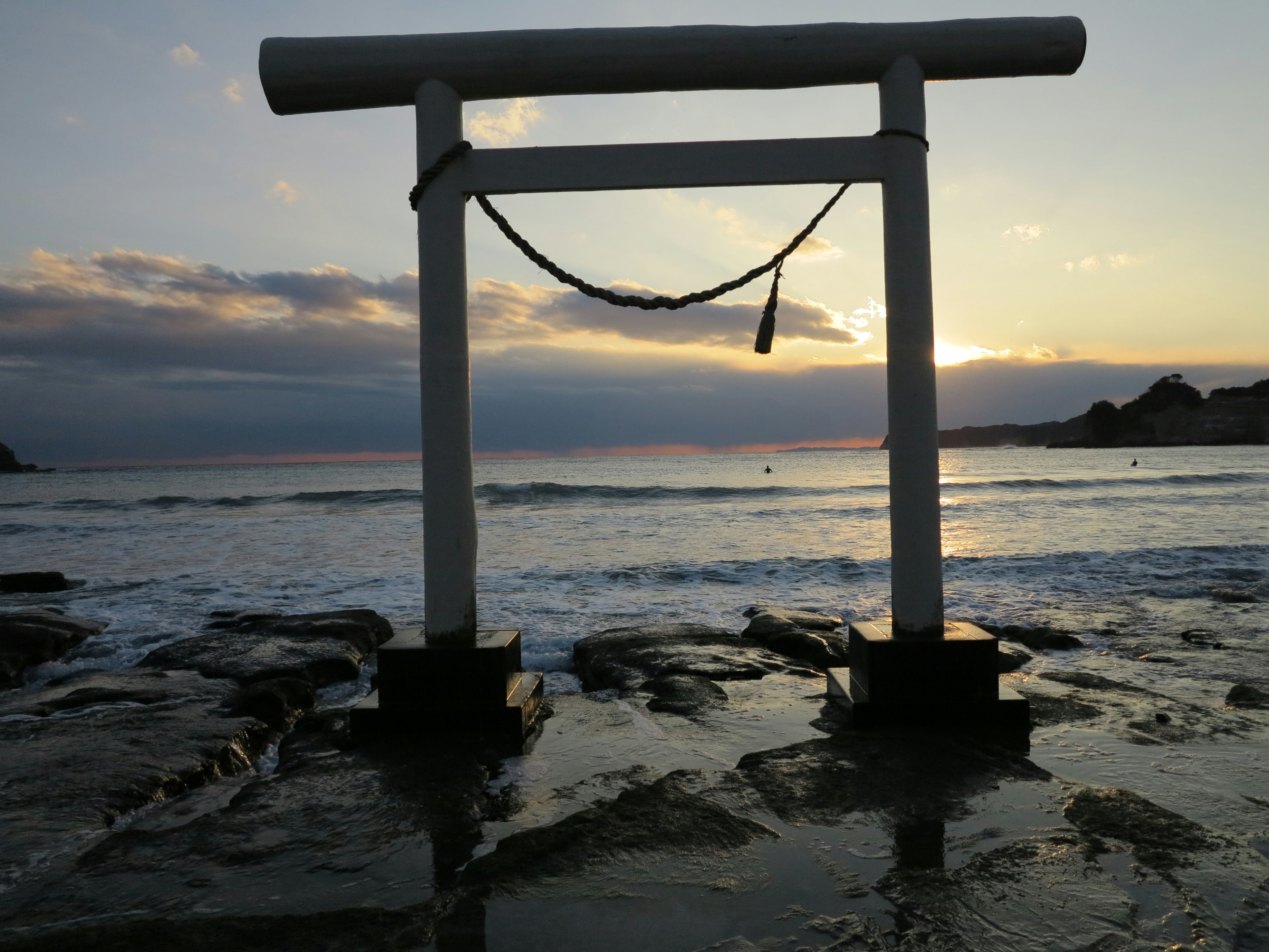 Portale torii bianco sulla spiaggia con un bel tramonto