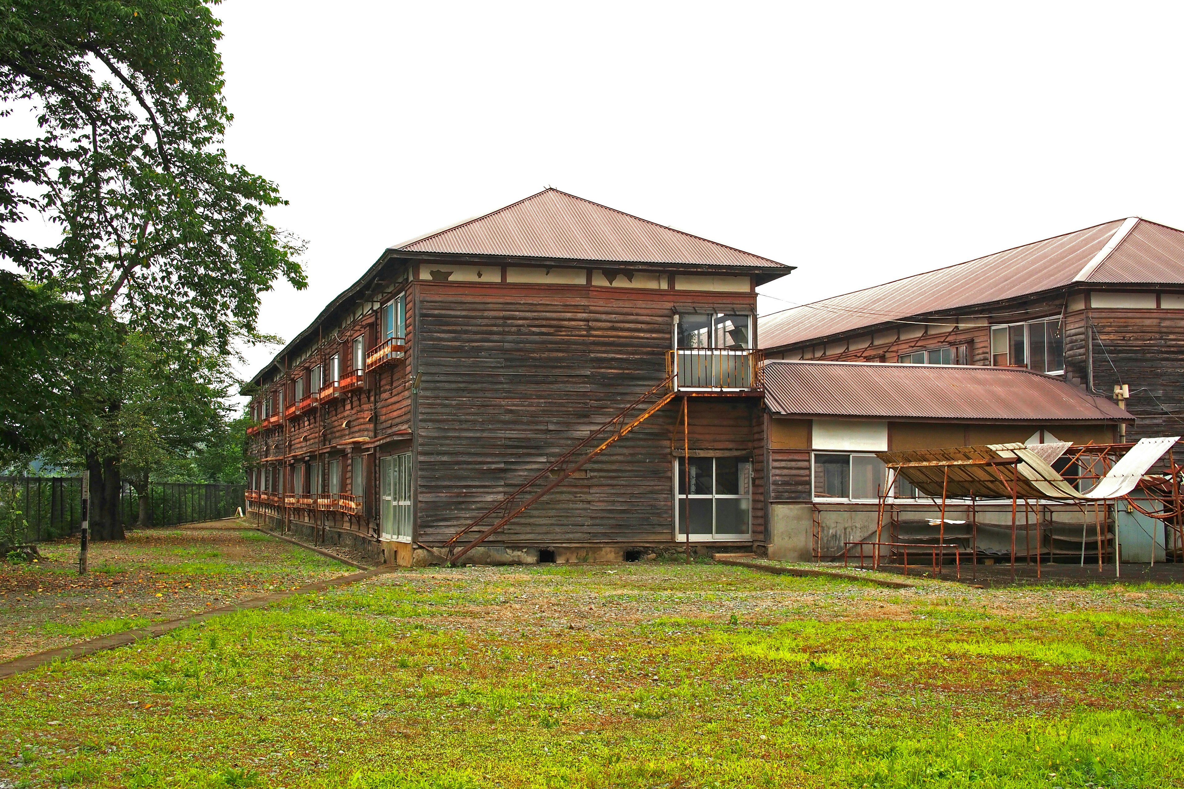 Exterior view of an old wooden building surrounded by greenery