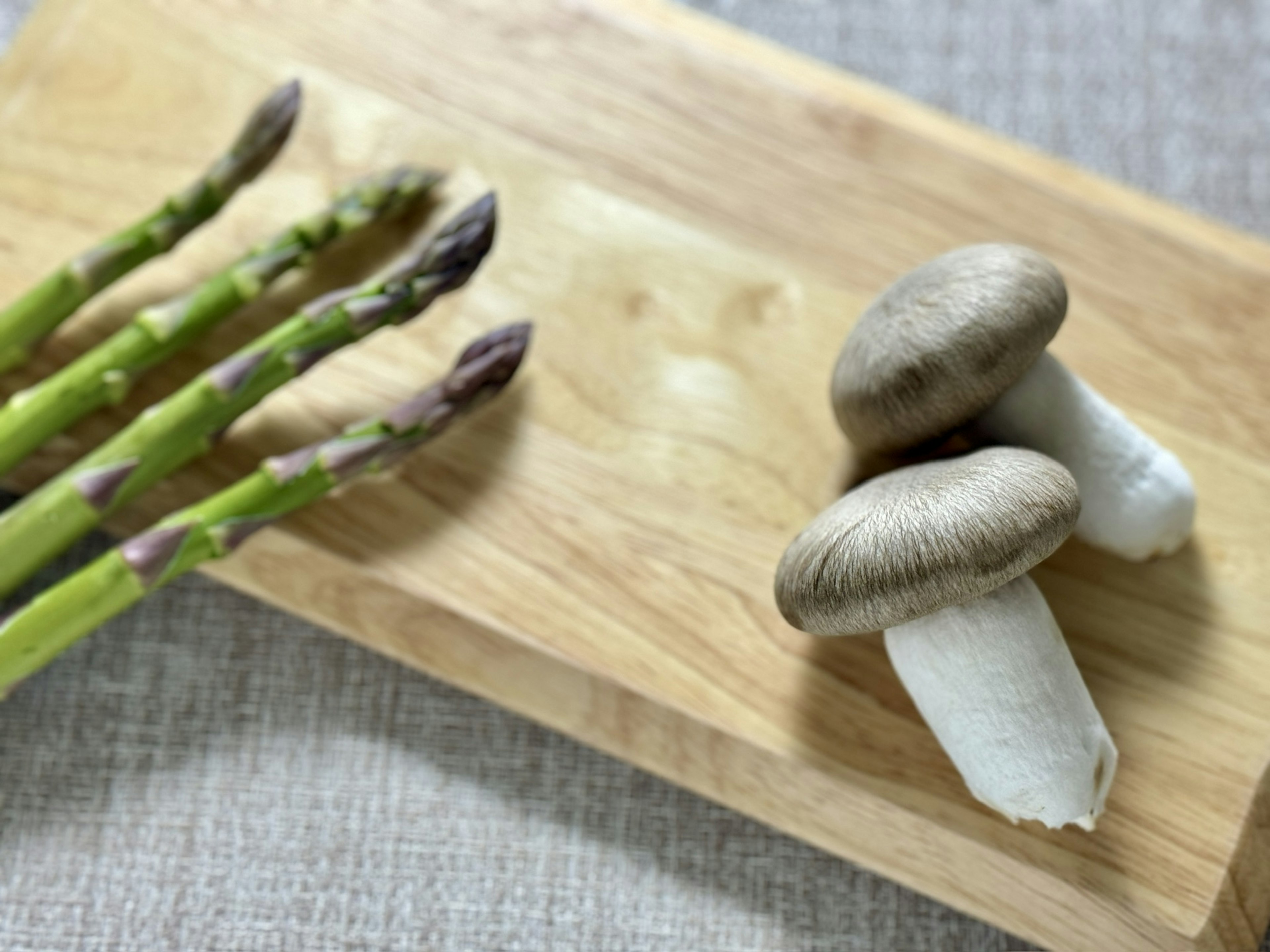 Asparagus and mushrooms arranged on a wooden board