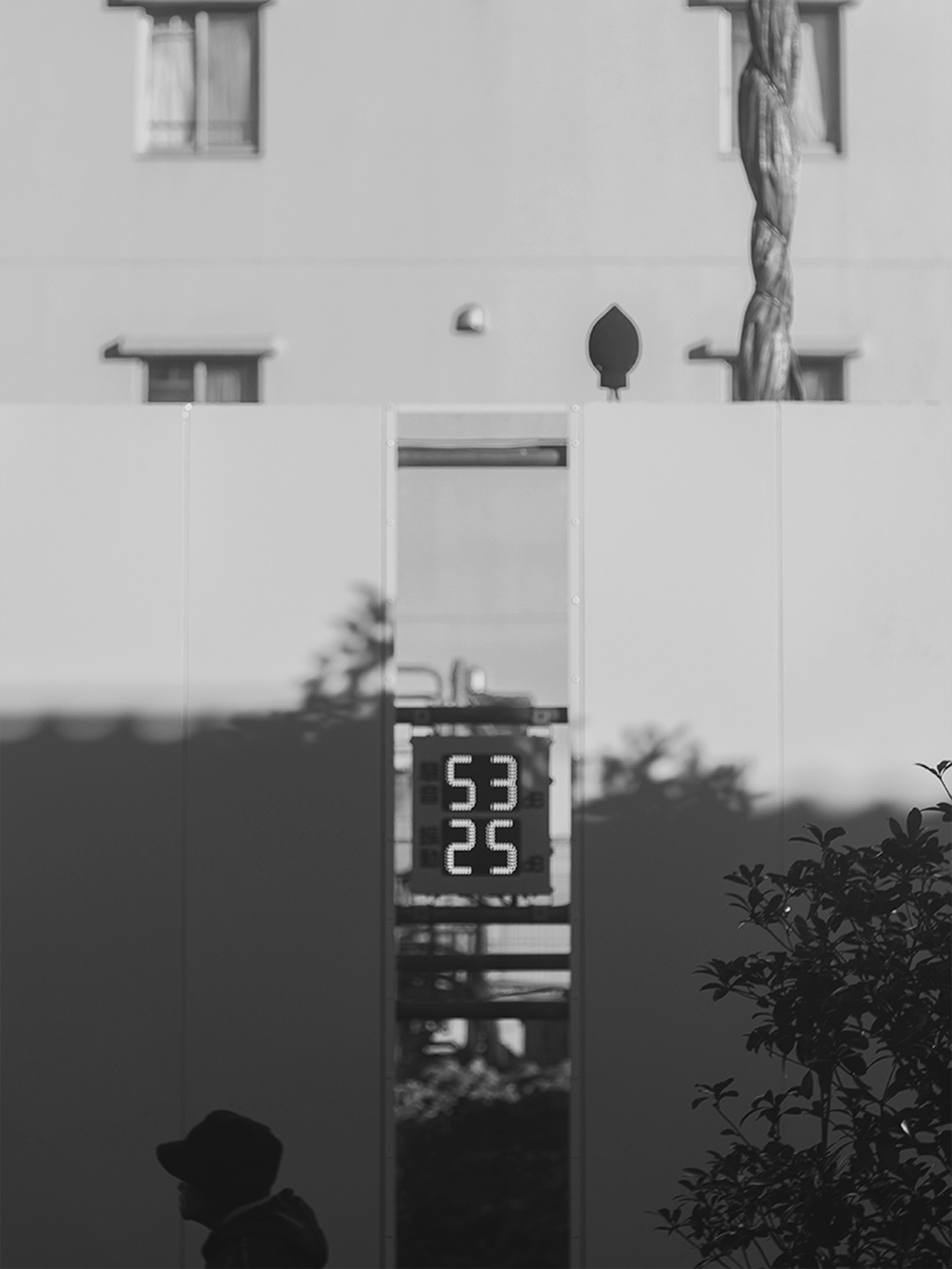 Urban scene featuring a digital clock display and shadows on a white wall