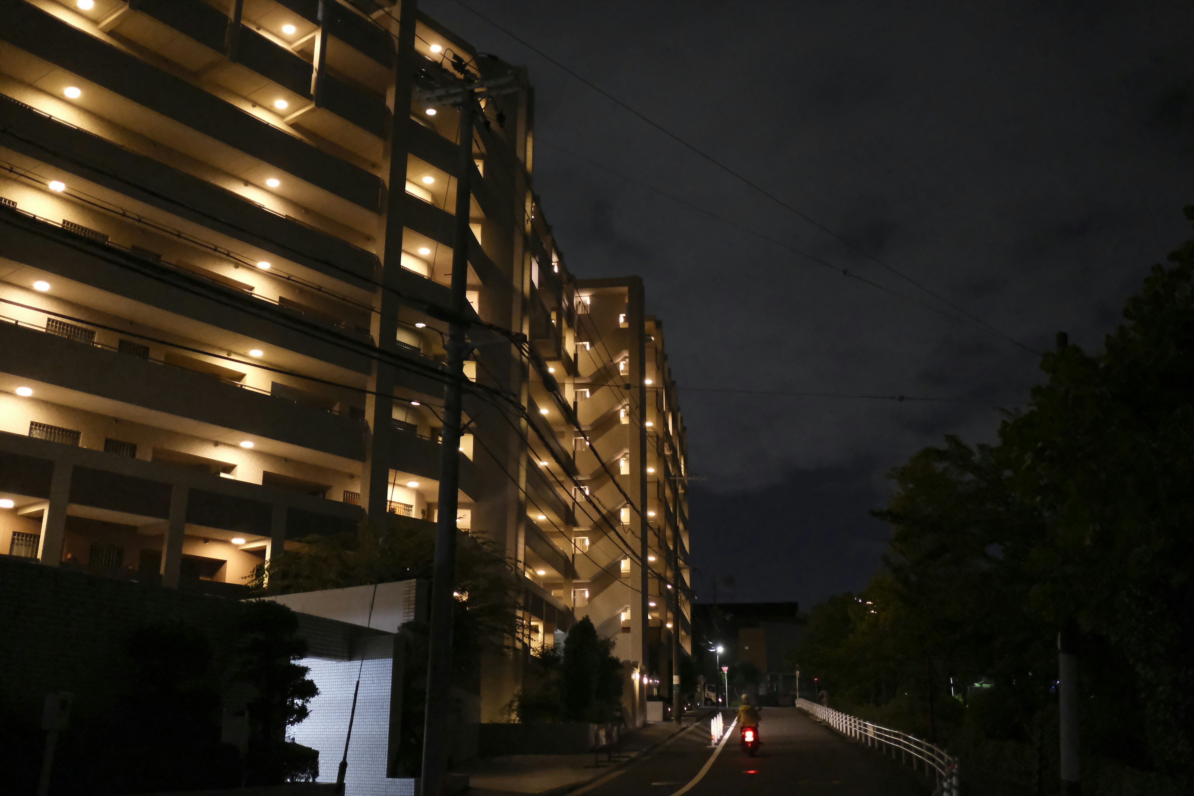 Vista nocturna de una calle con un edificio de apartamentos iluminado