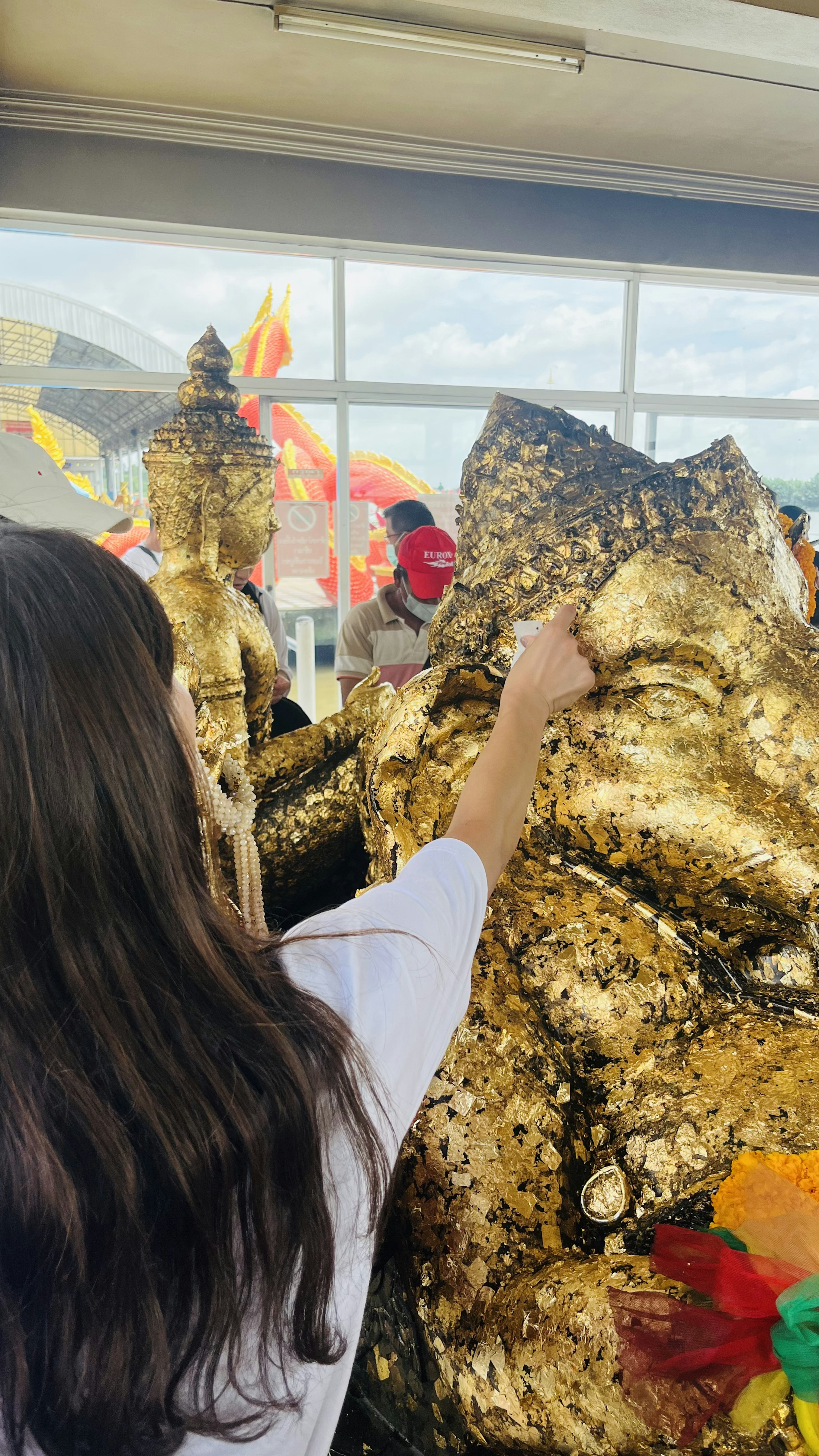 金色の仏像に触れる女性と鮮やかな装飾