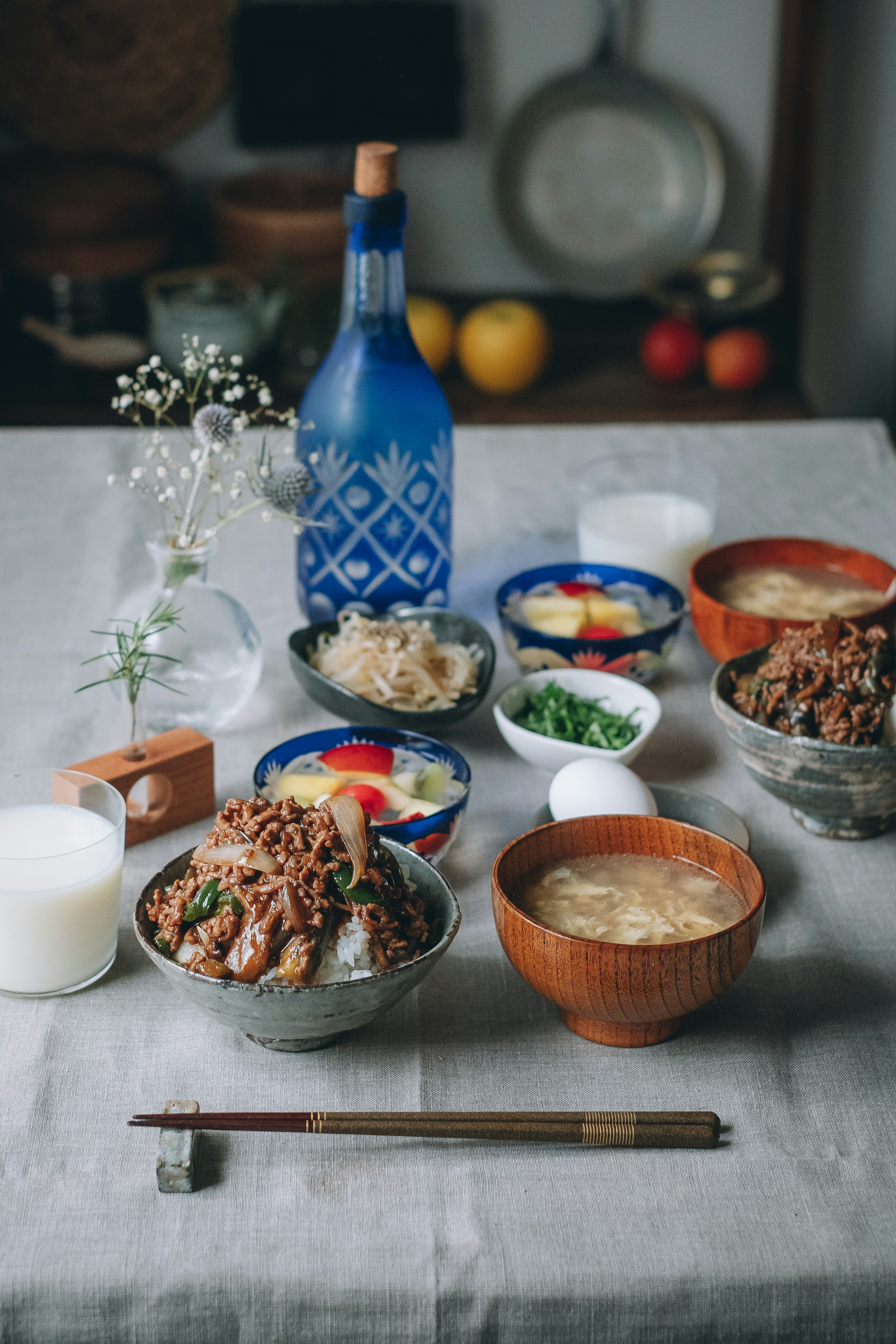 Une sélection de plats japonais sur une table avec une bouteille de saké bleue