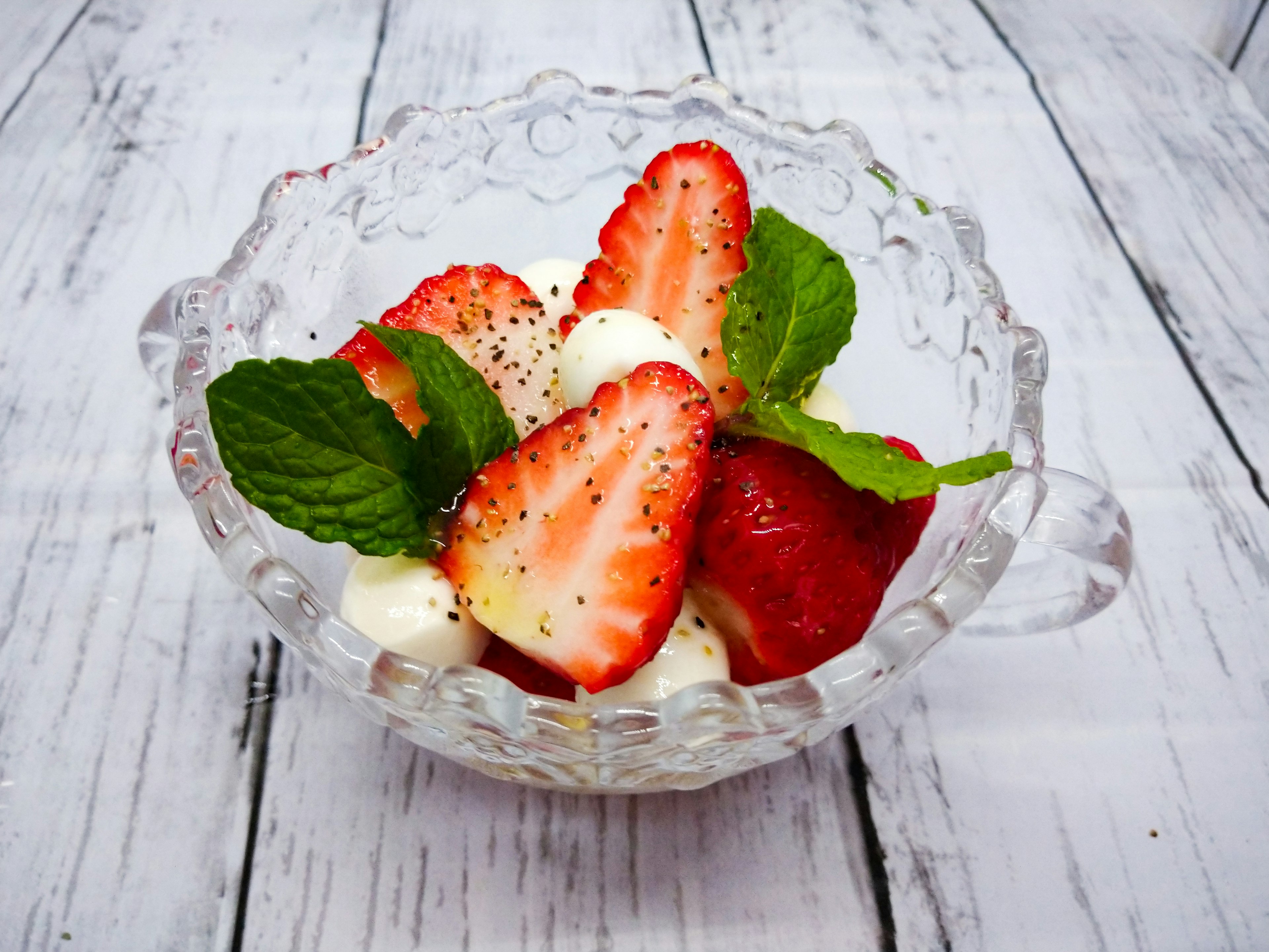 Mangkuk stroberi dan daun mint dengan krim kocok