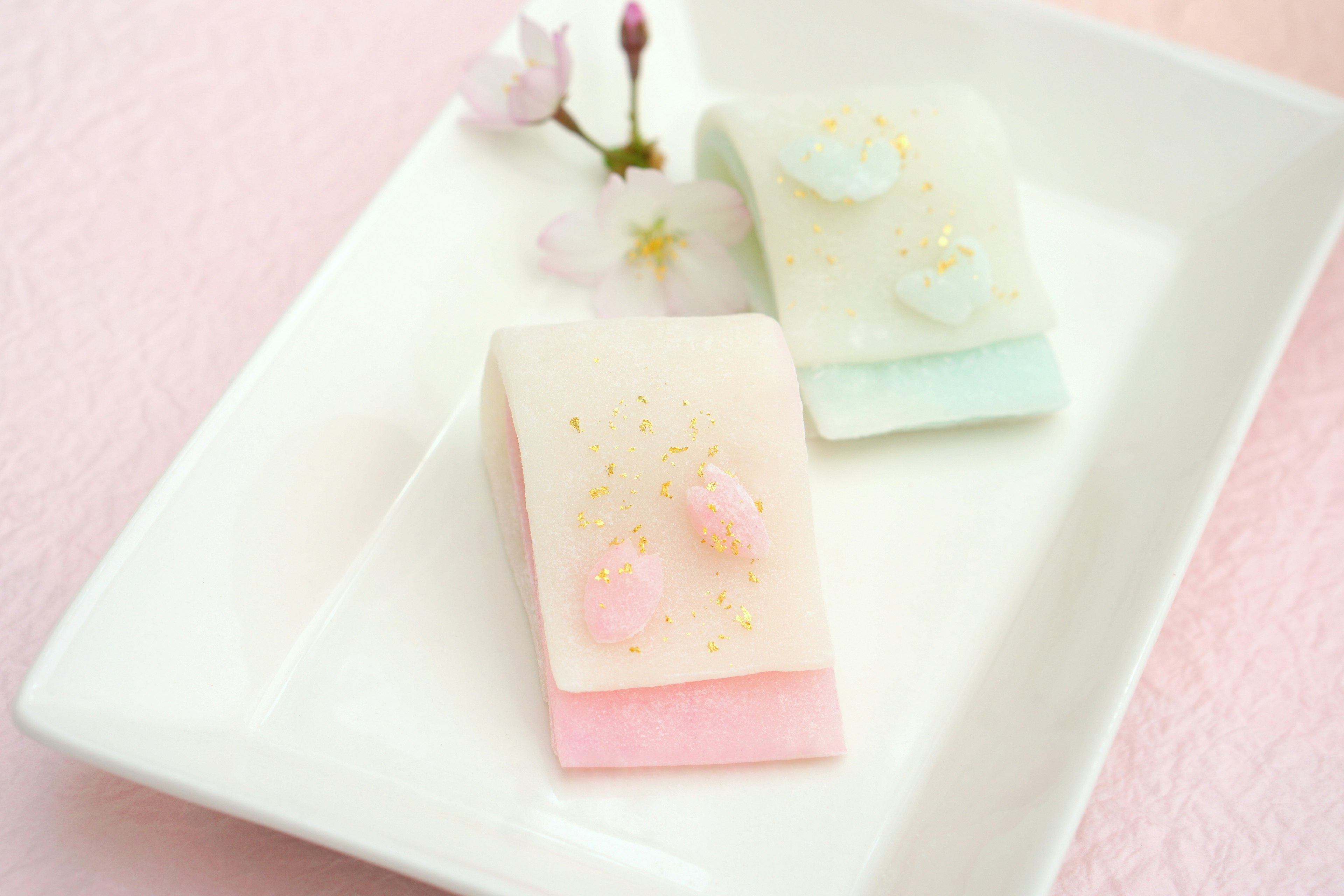 Delicate Japanese sweets adorned with cherry blossoms on a white plate