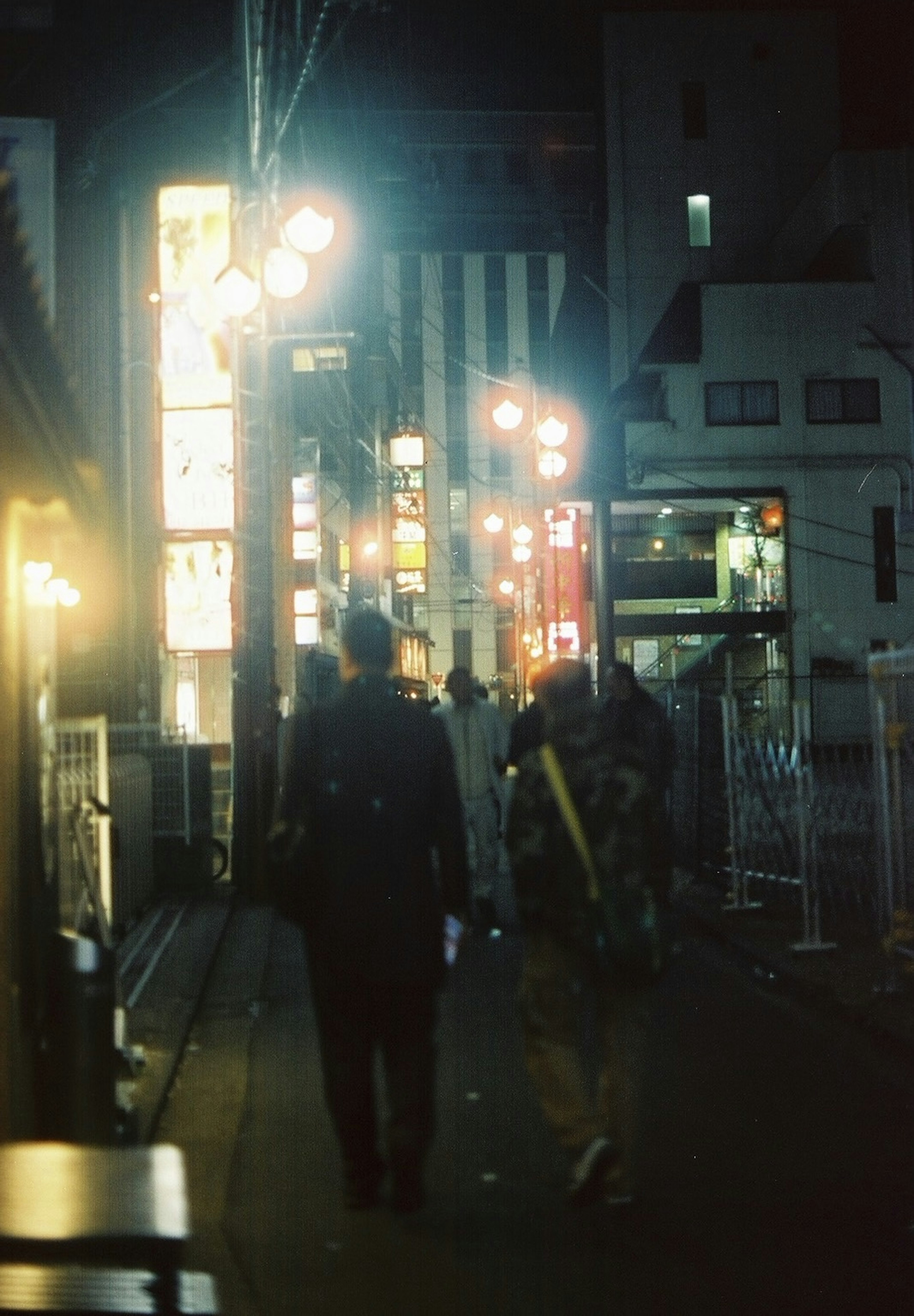 Personas caminando en una calle nocturna con letreros brillantes