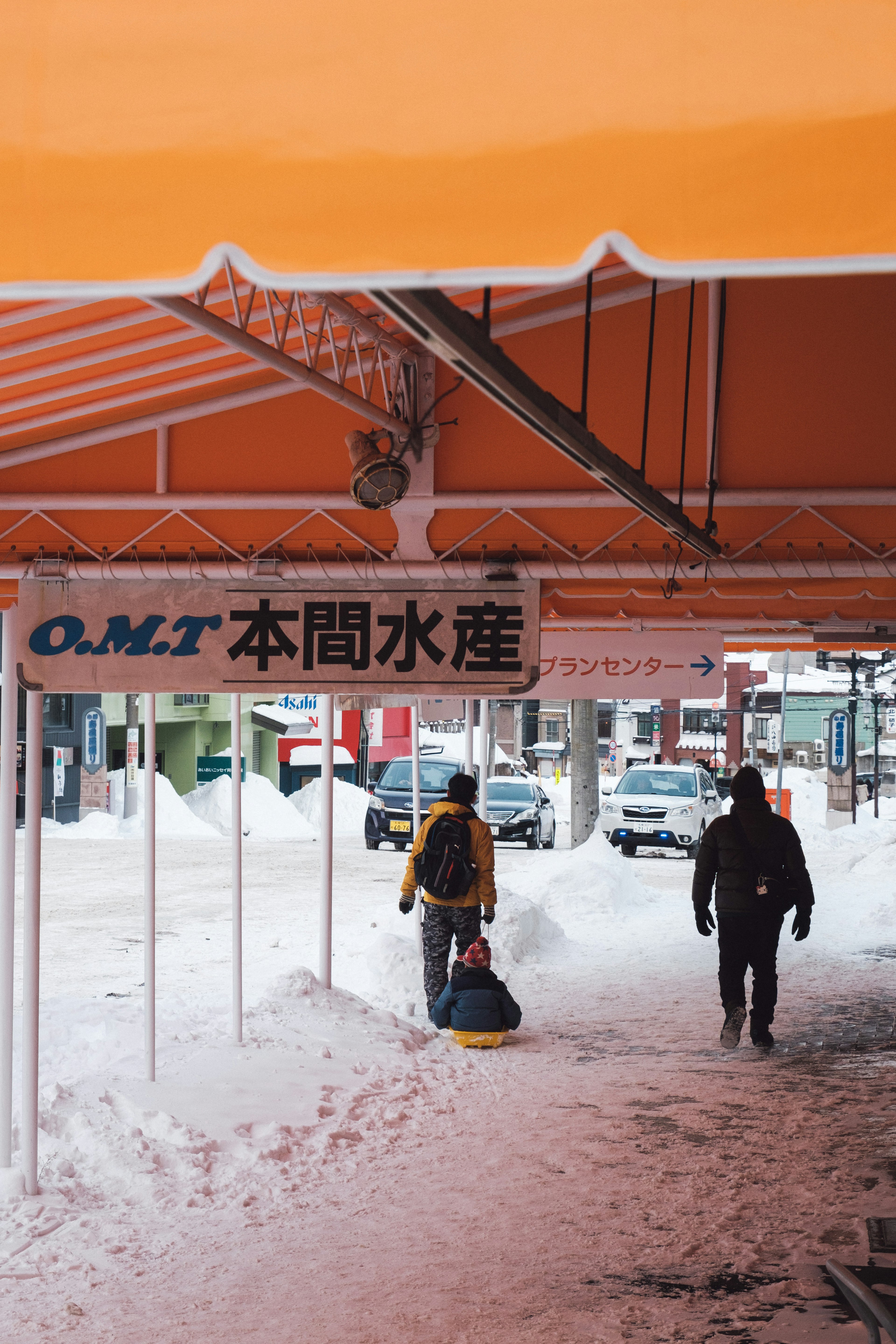 雪の中を歩く人々とオレンジ色のテントがある風景