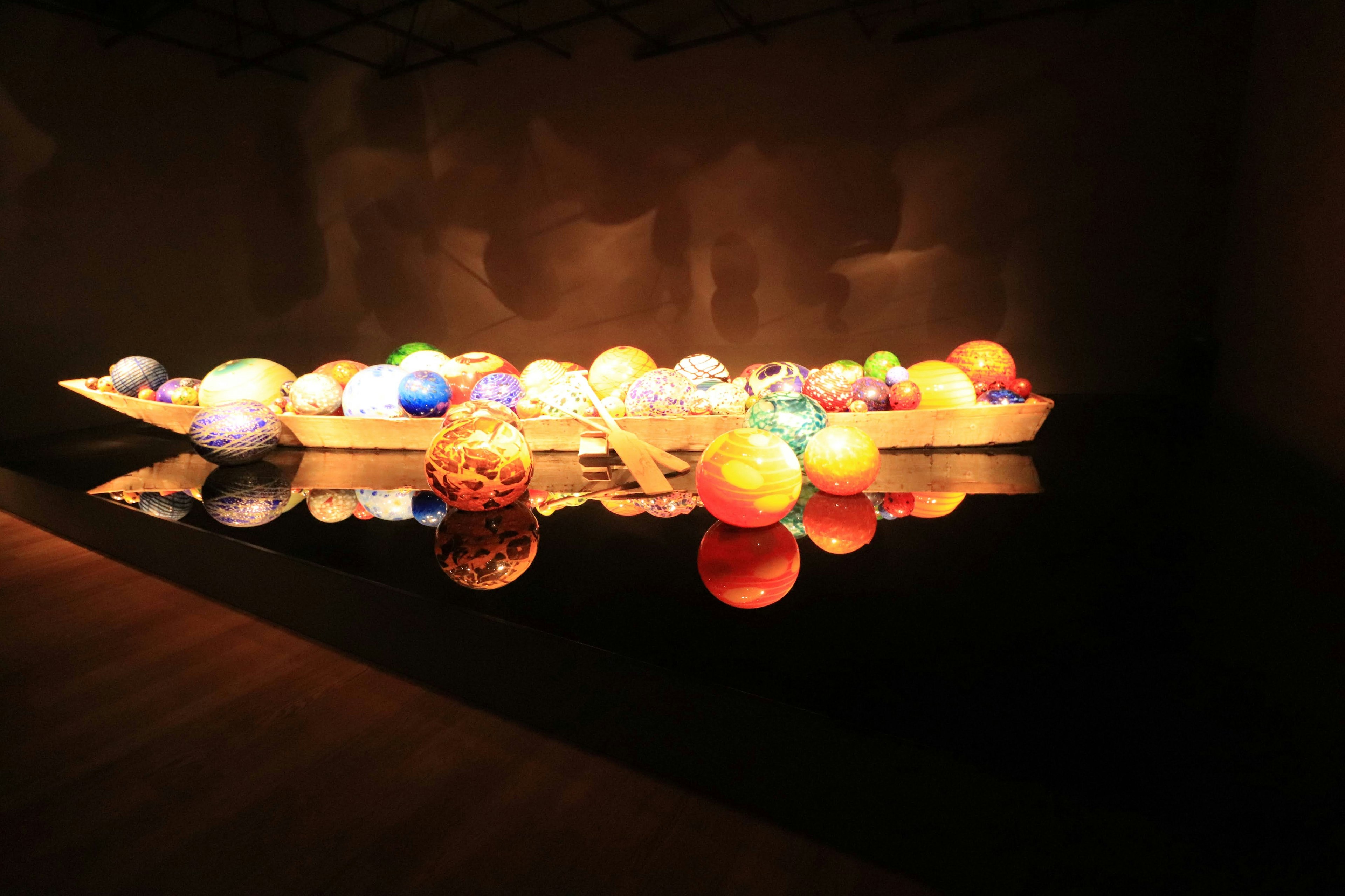 Art installation featuring colorful spheres on a wooden boat