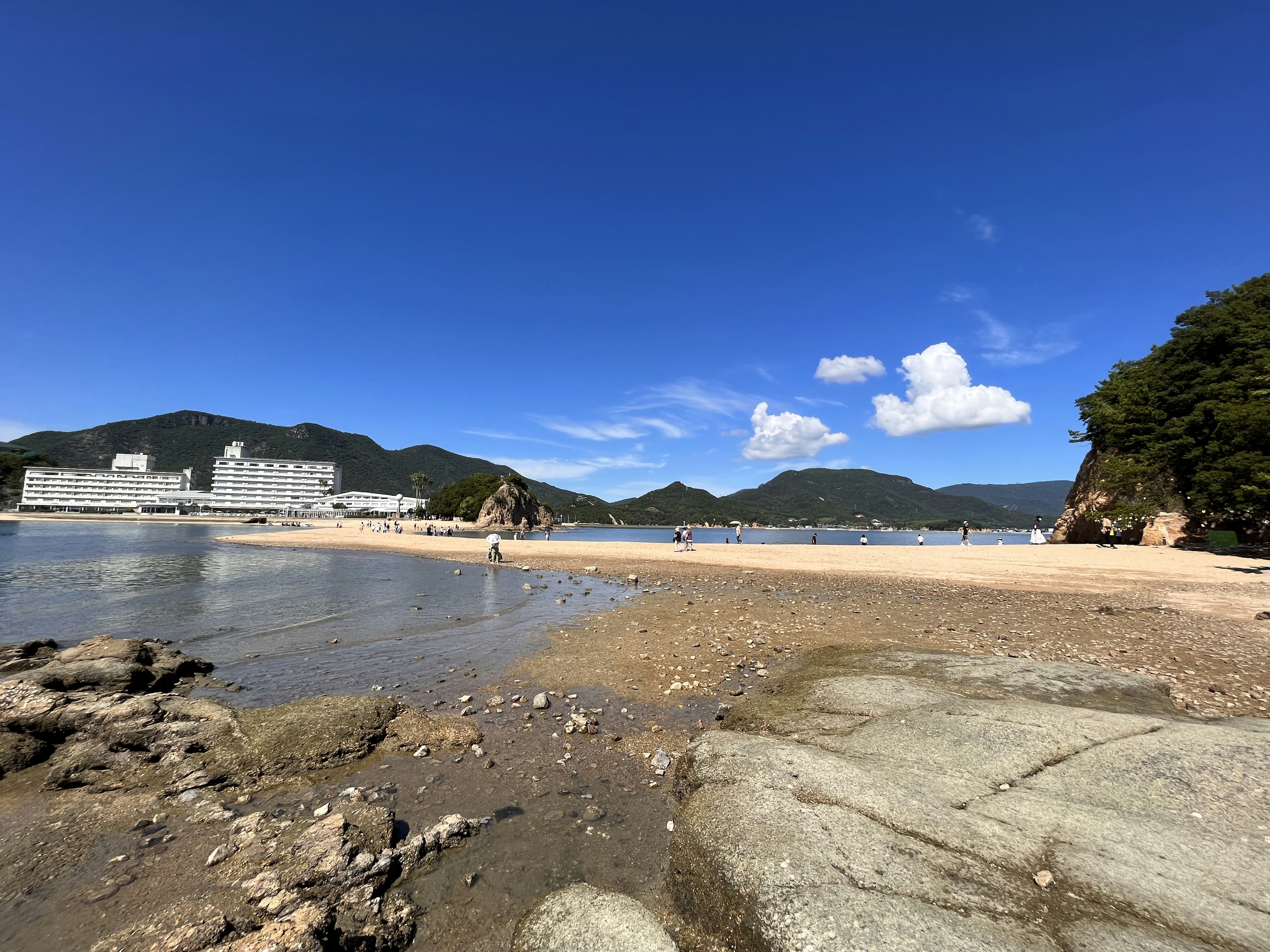 青空と白い雲の下に広がる海岸風景 岩と砂浜が特徴的