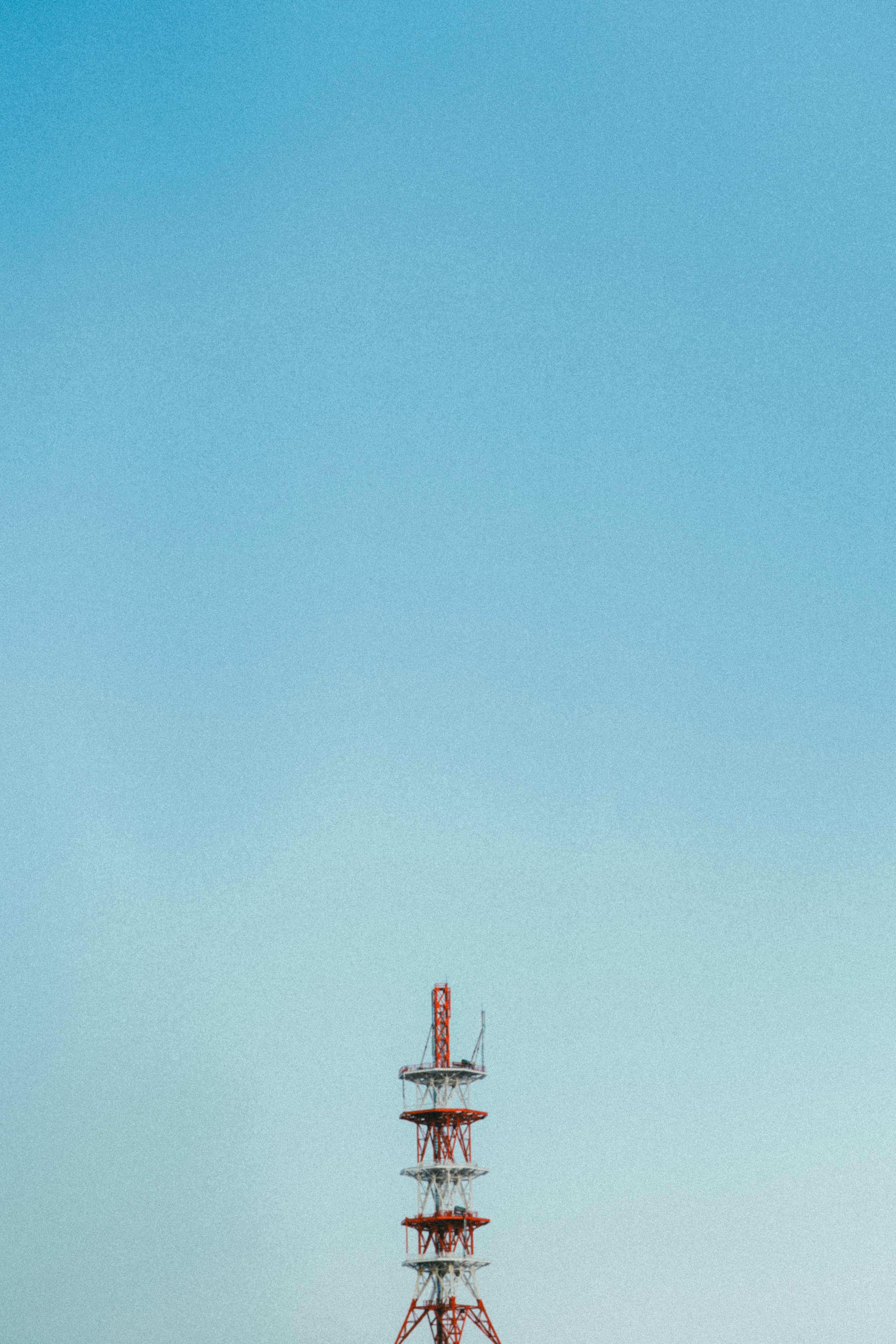 Red communication tower against a clear blue sky