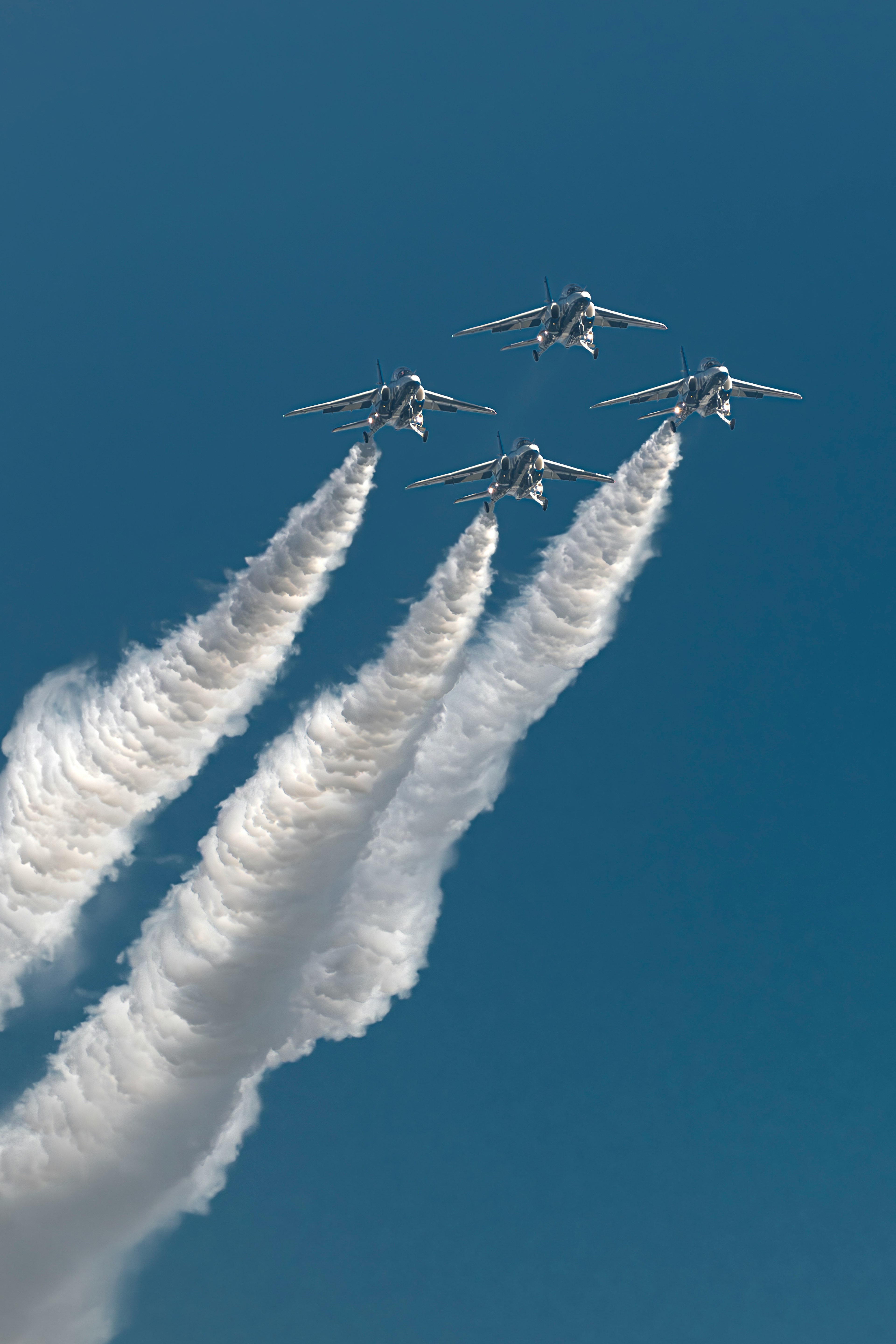 青空に白い煙を出しながら飛行する4機の戦闘機