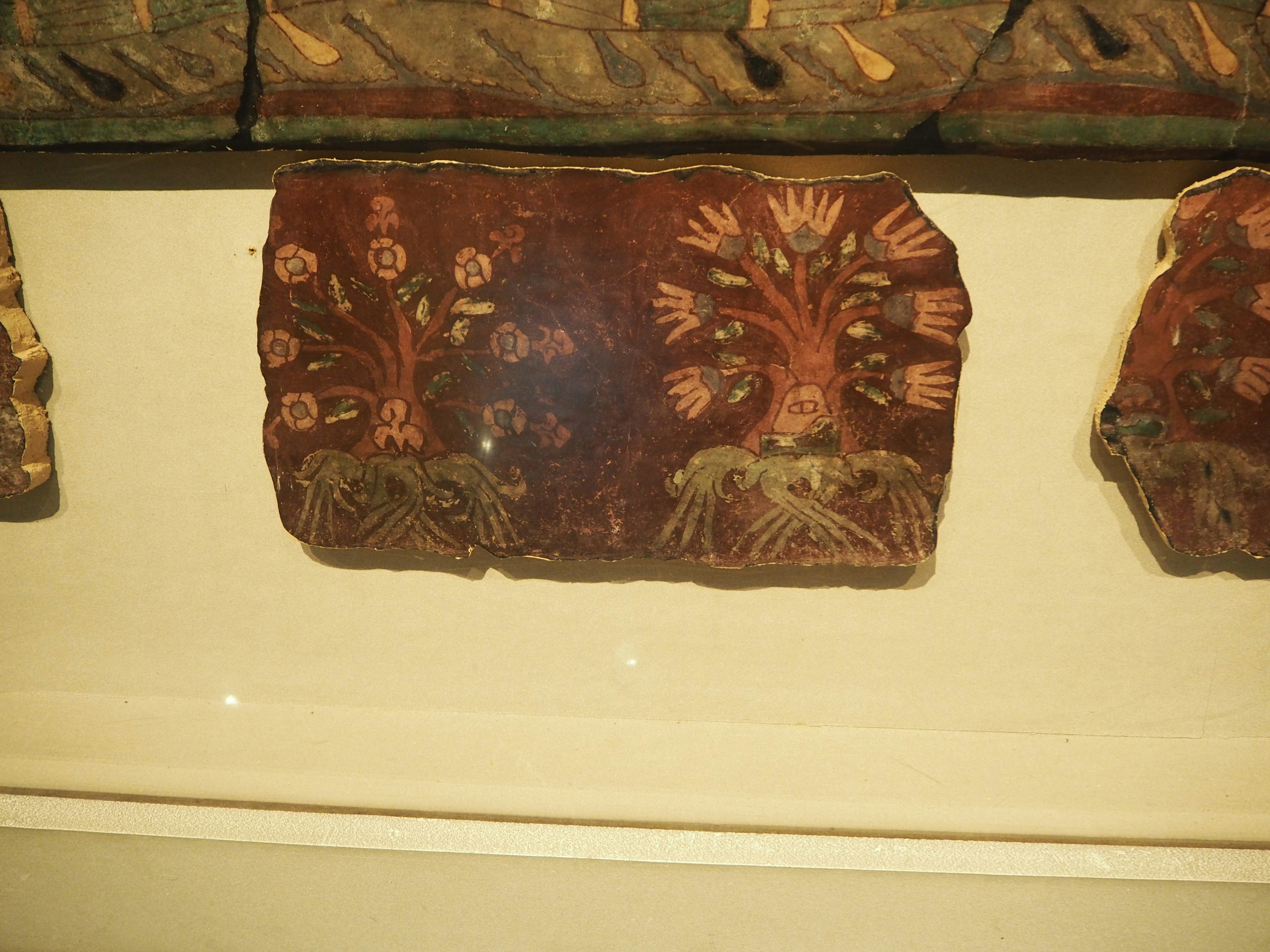 Ancient decorative tile featuring floral and tree patterns