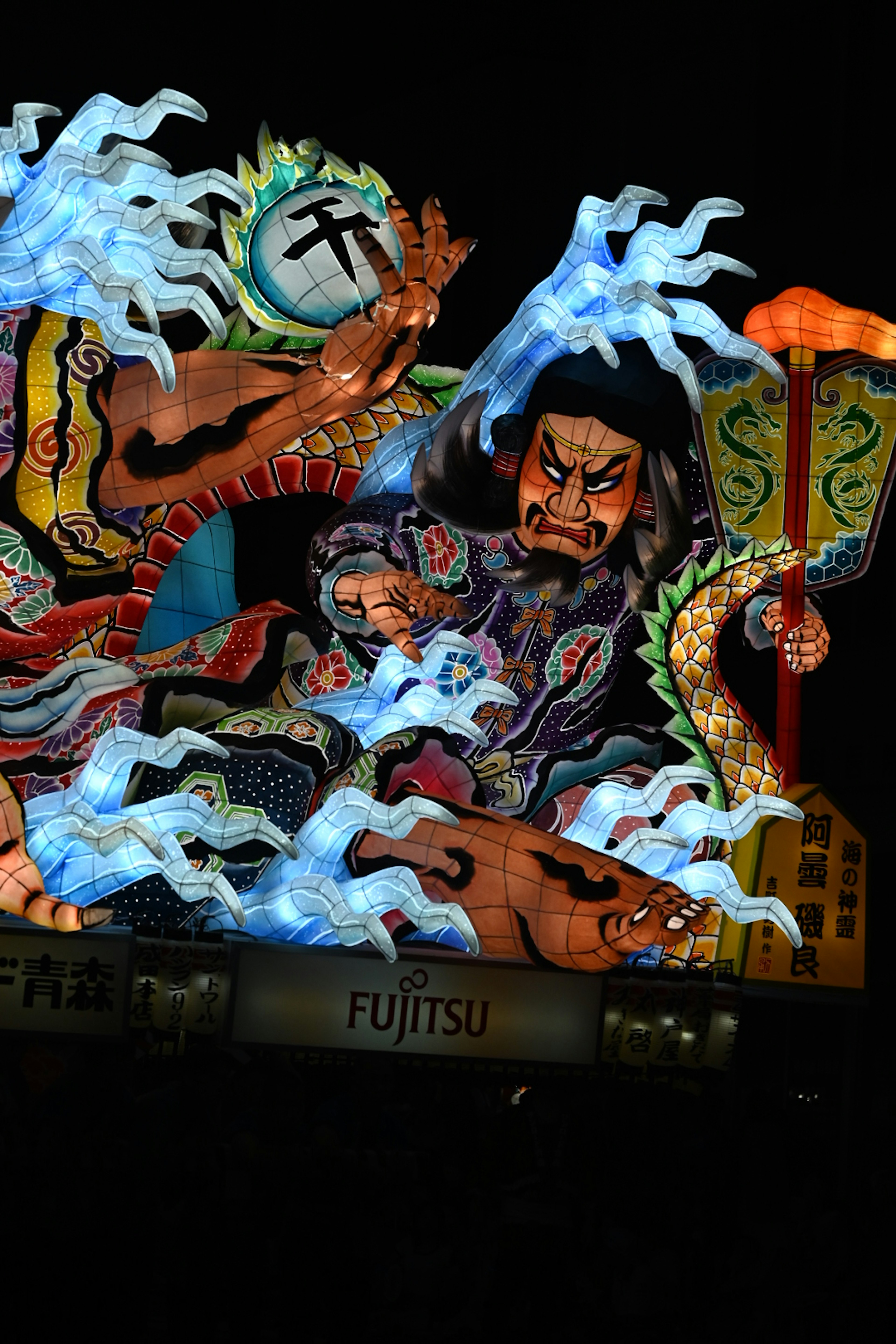 Un grand char du festival Nebuta d'Aomori représentant un guerrier au milieu de vagues bleues et de couleurs vives