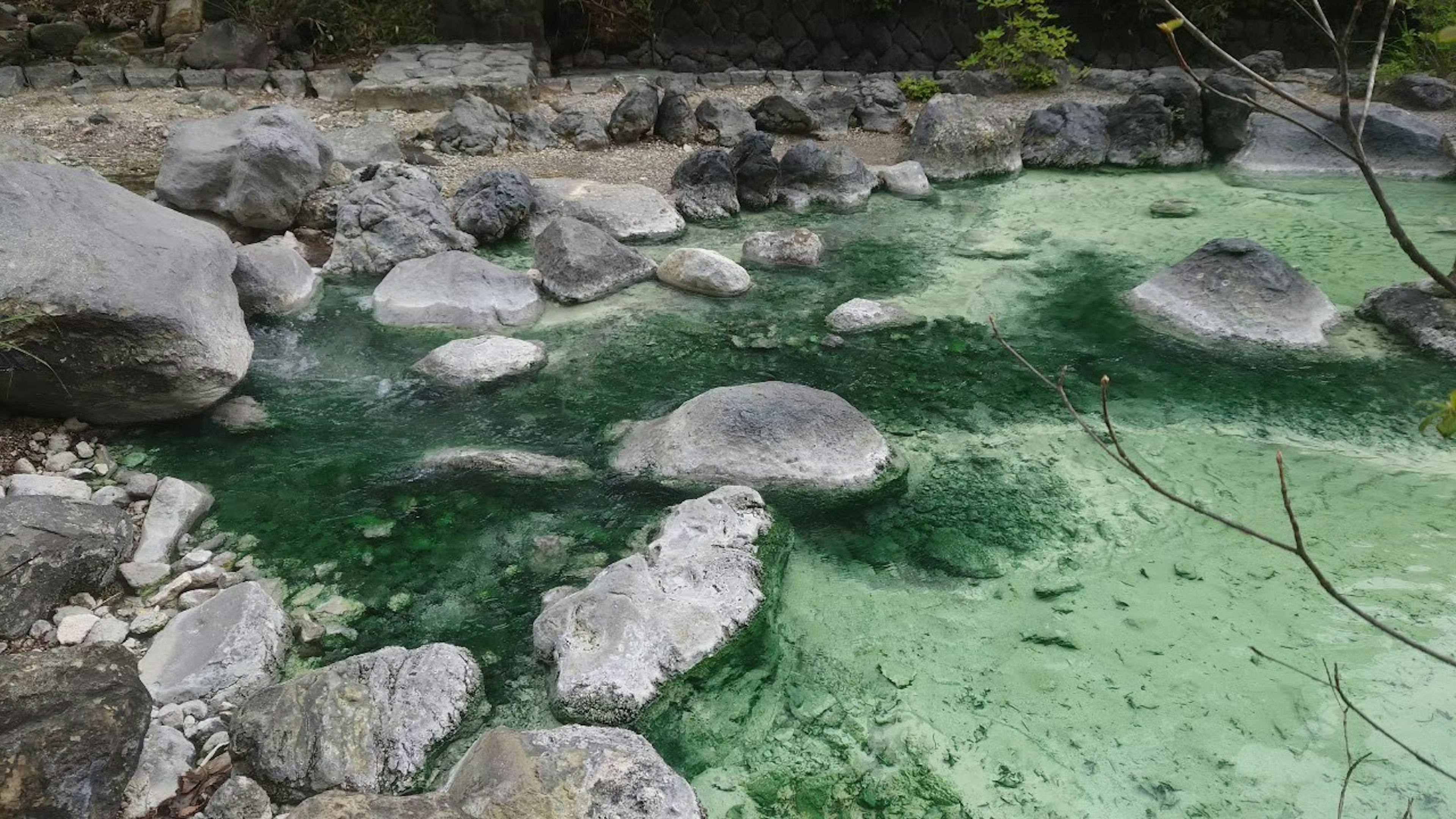 Natural landscape with greenish water and large scattered rocks