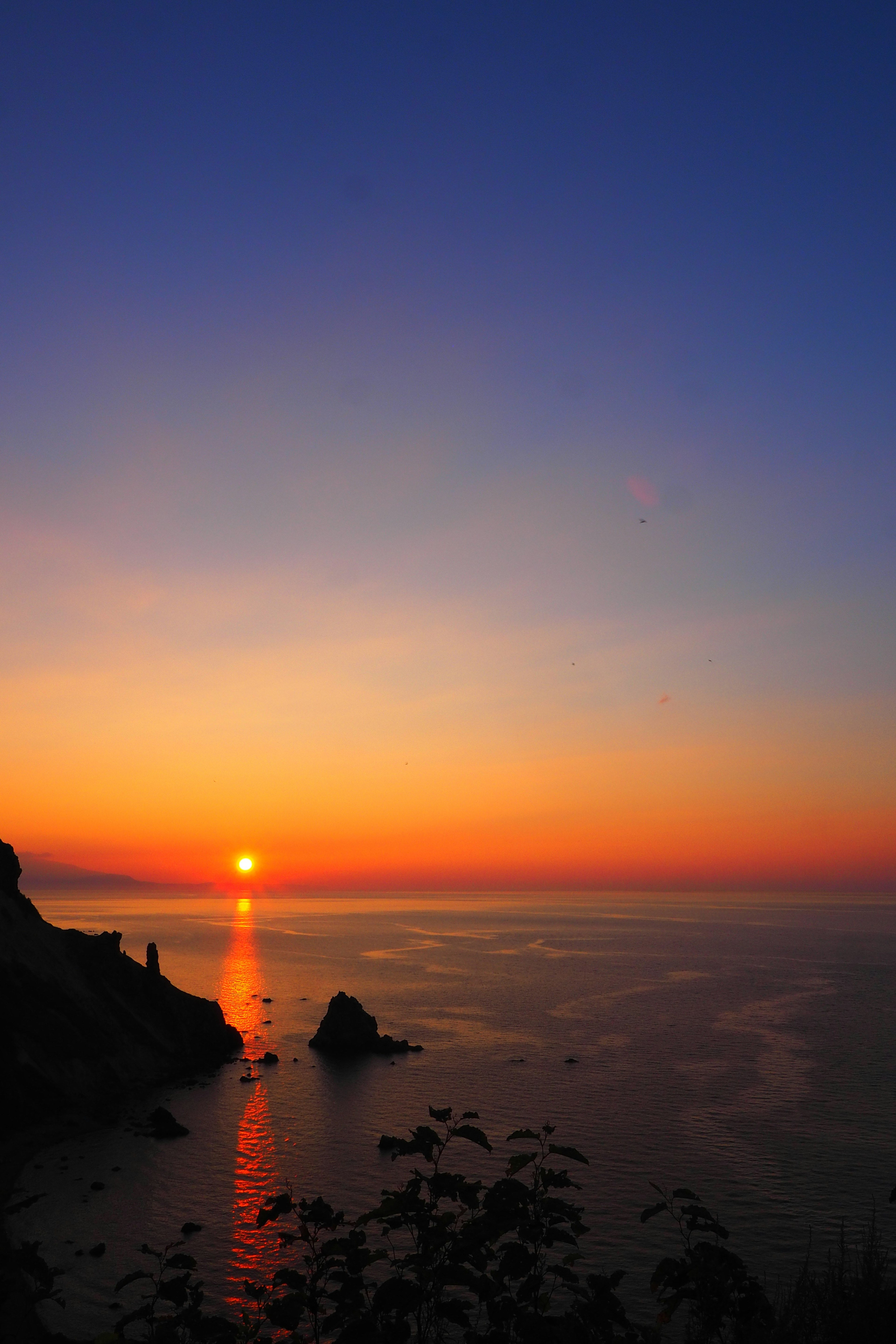 A beautiful sunset over the ocean with silhouettes of rocks