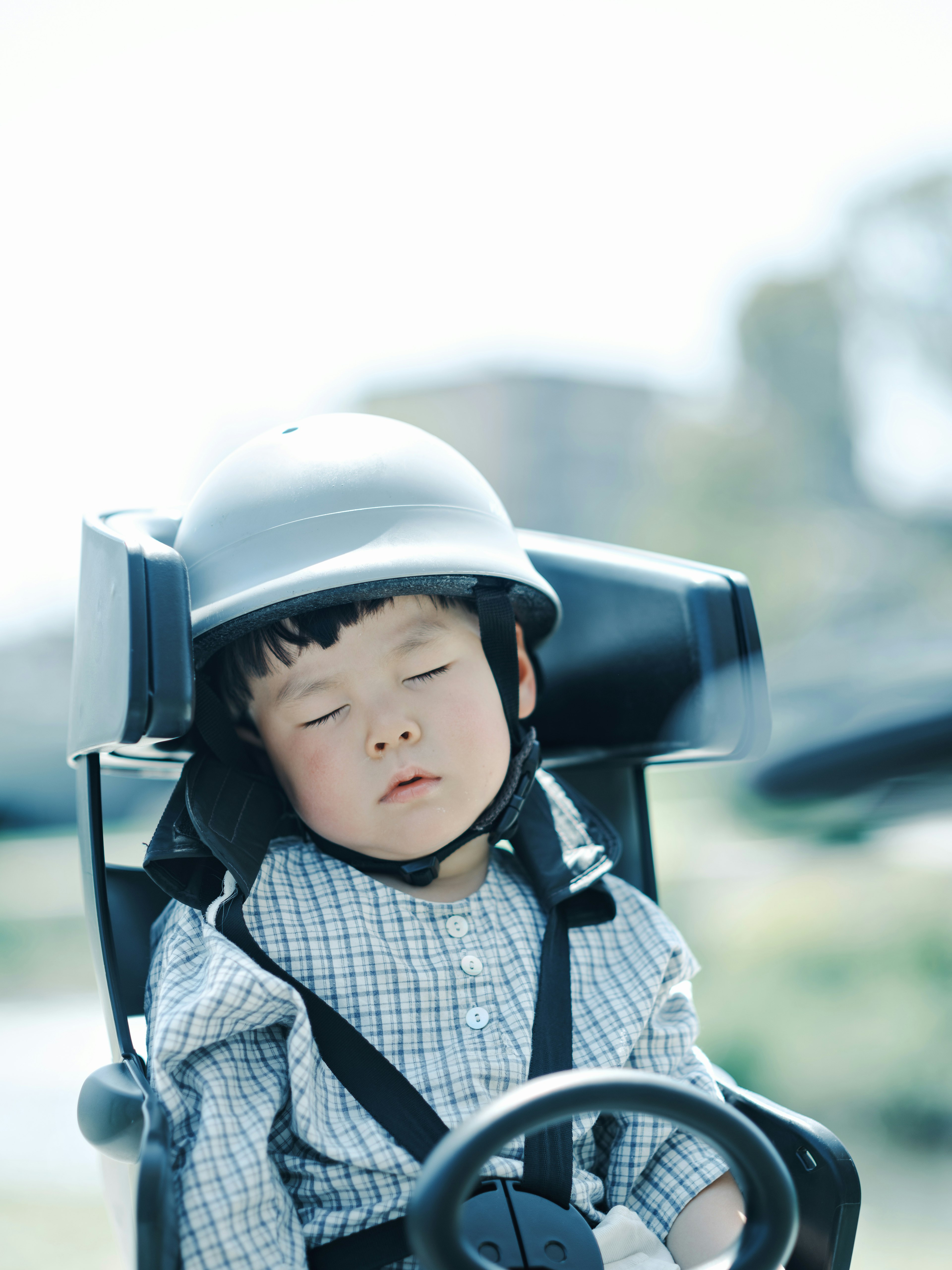 Seorang anak yang tidur mengenakan helm duduk di kereta dorong