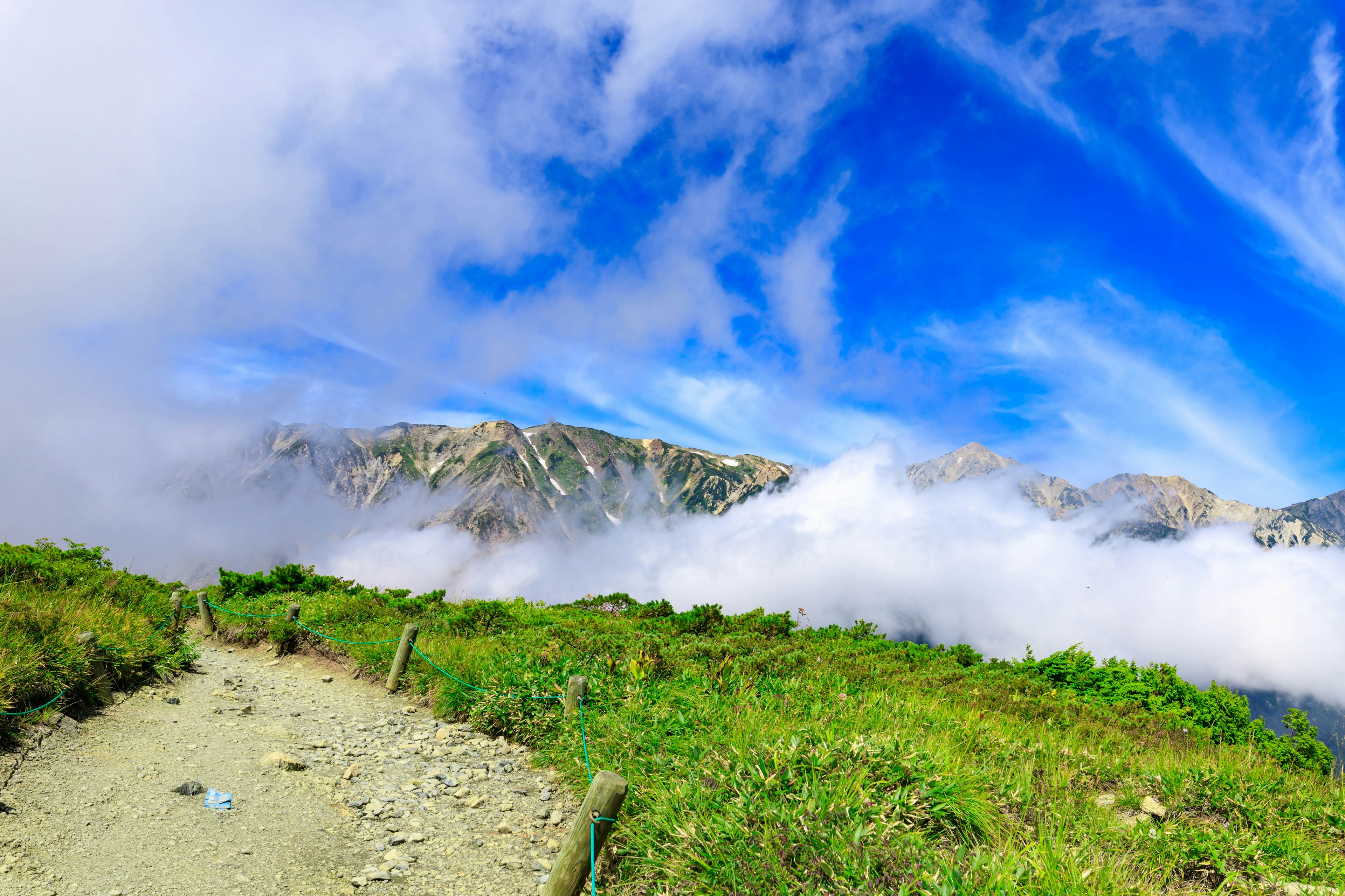 Paesaggio montano con cielo blu e nuvole erba verde e un sentiero