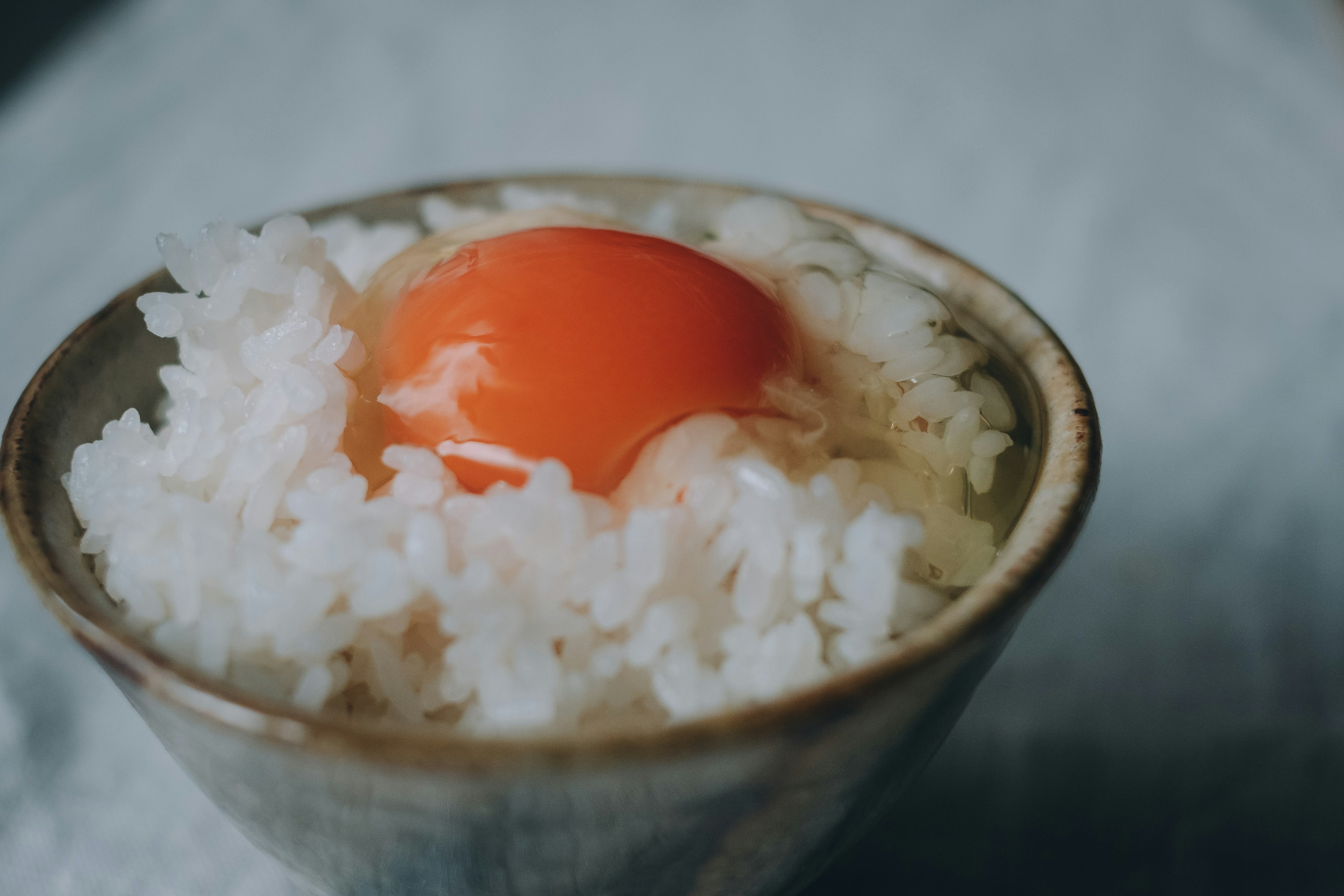 白いご飯の上に鮮やかなオレンジの卵黄が乗った陶器のボウル