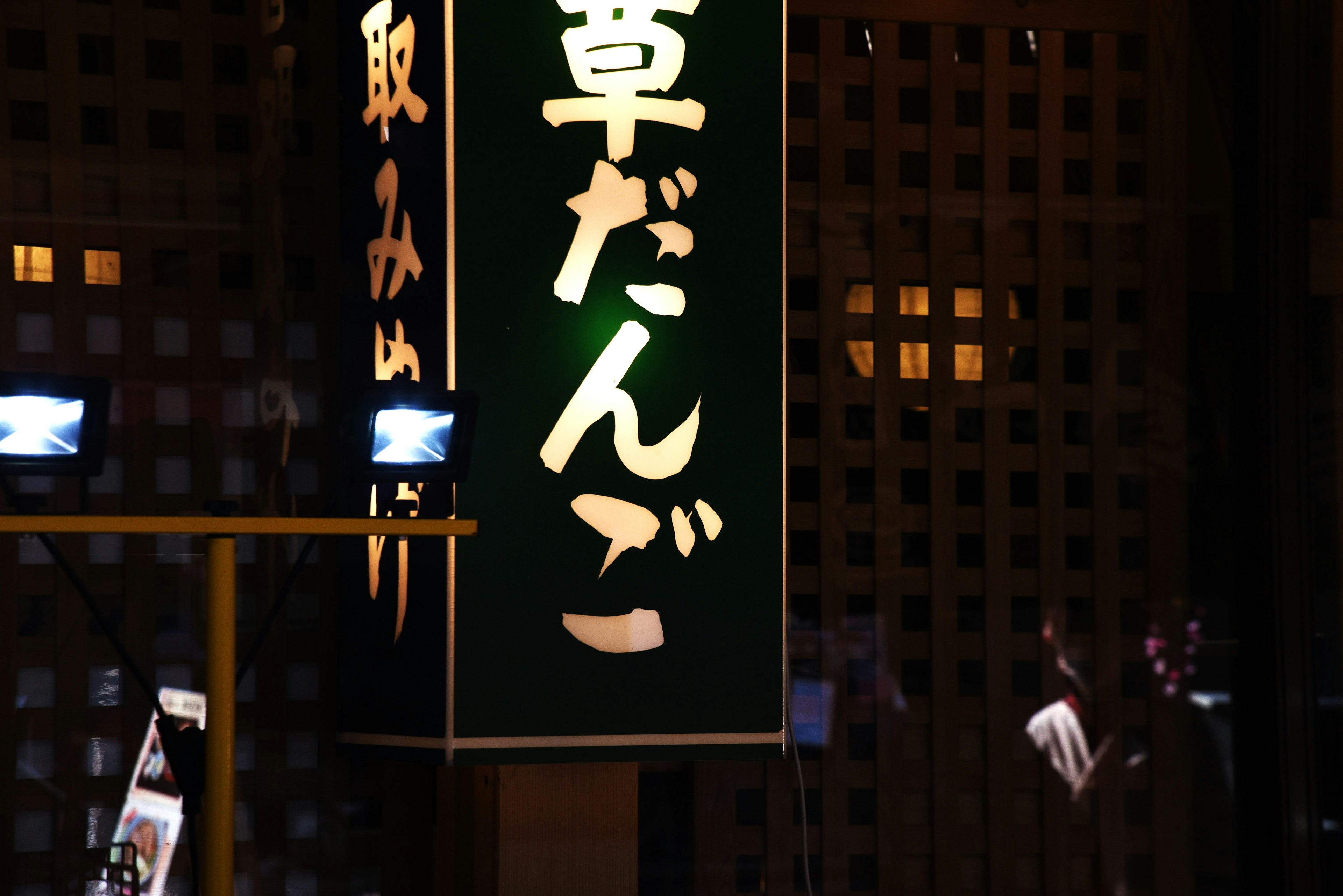 Illuminated sign for grass dumplings in a dark setting