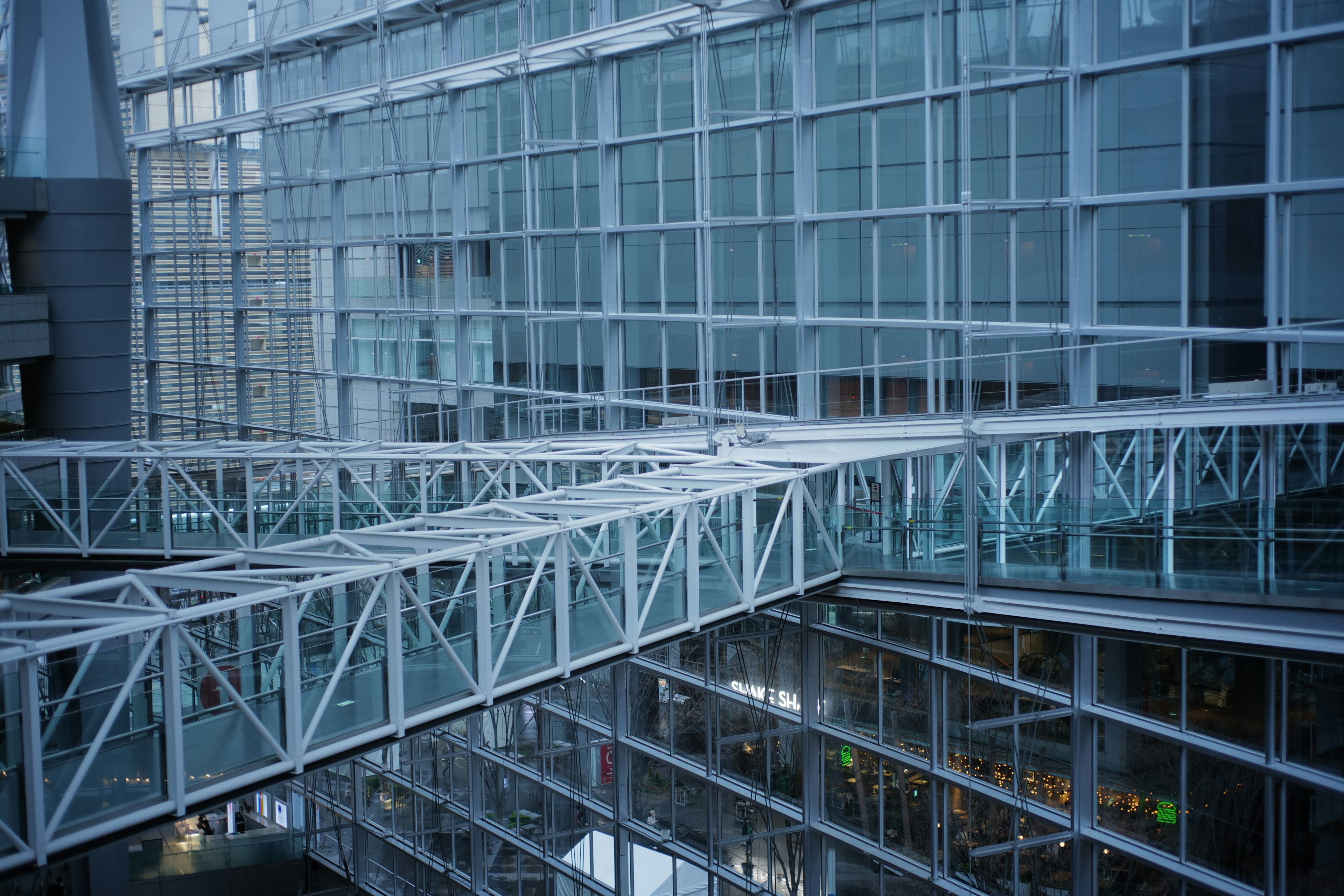 Modern building interior featuring glass walls and a white pedestrian bridge