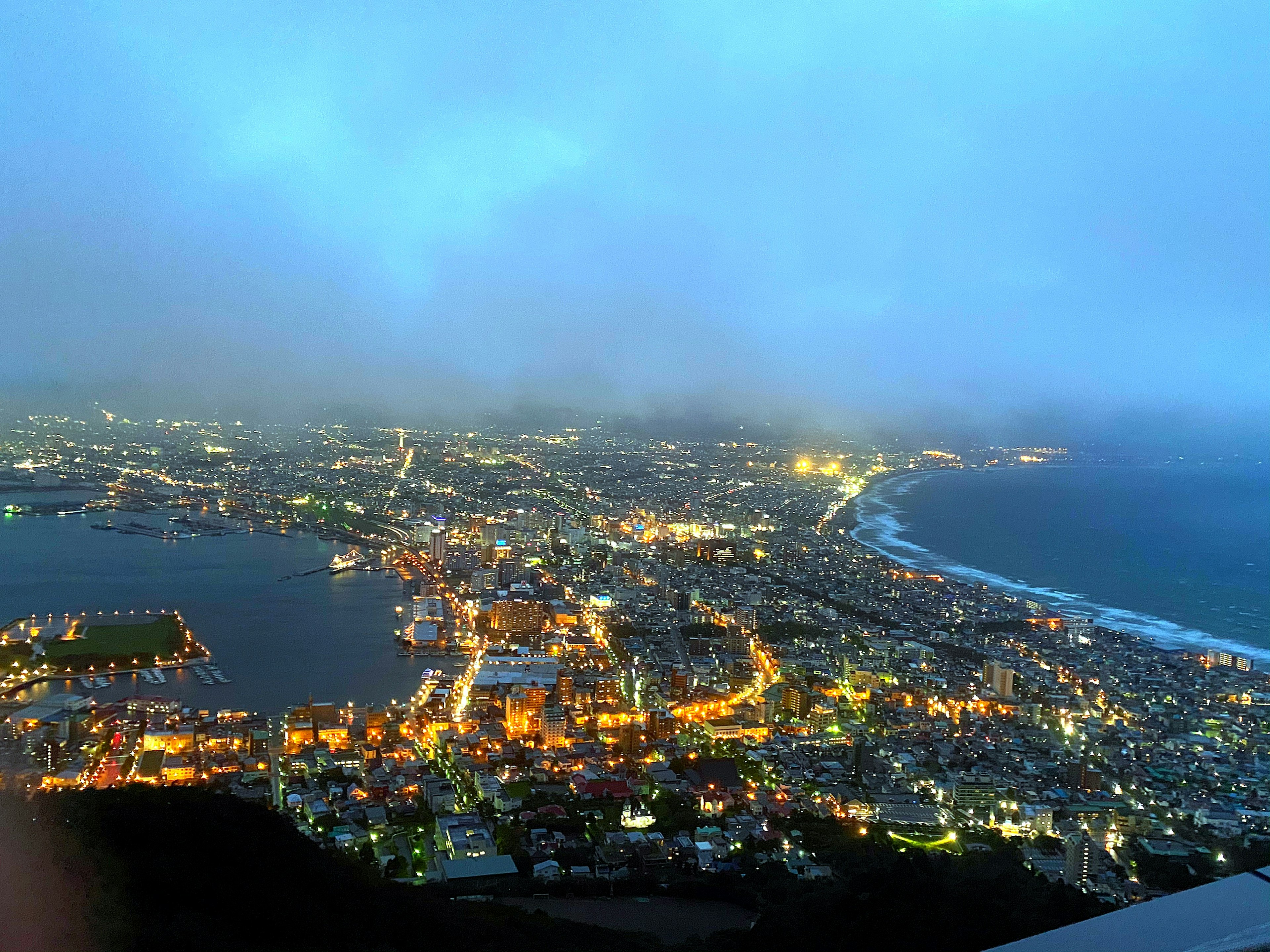 夜景の都市のパノラマが広がる青い空と雲の中の光