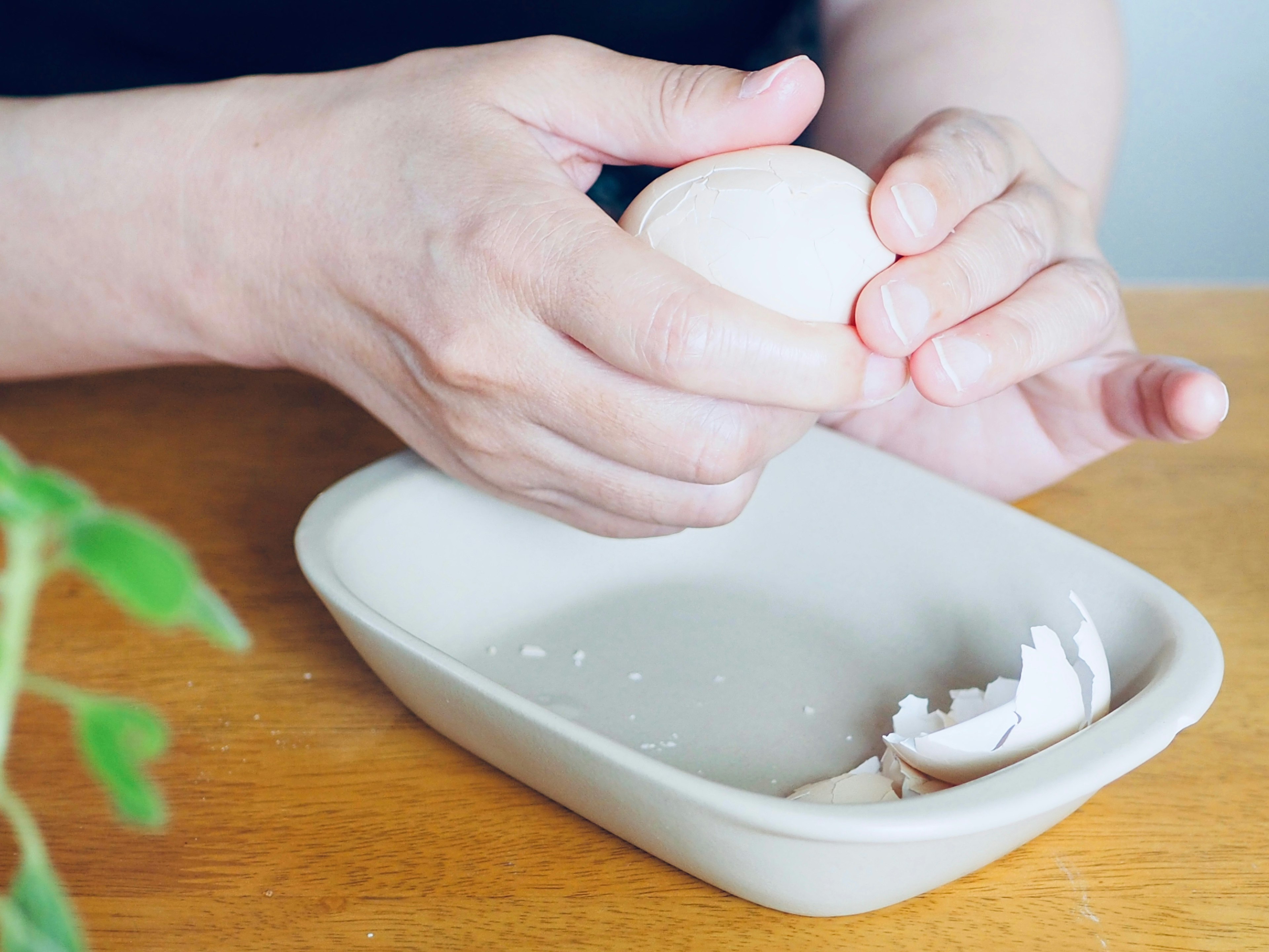 Manos rompiendo un huevo sobre un plato