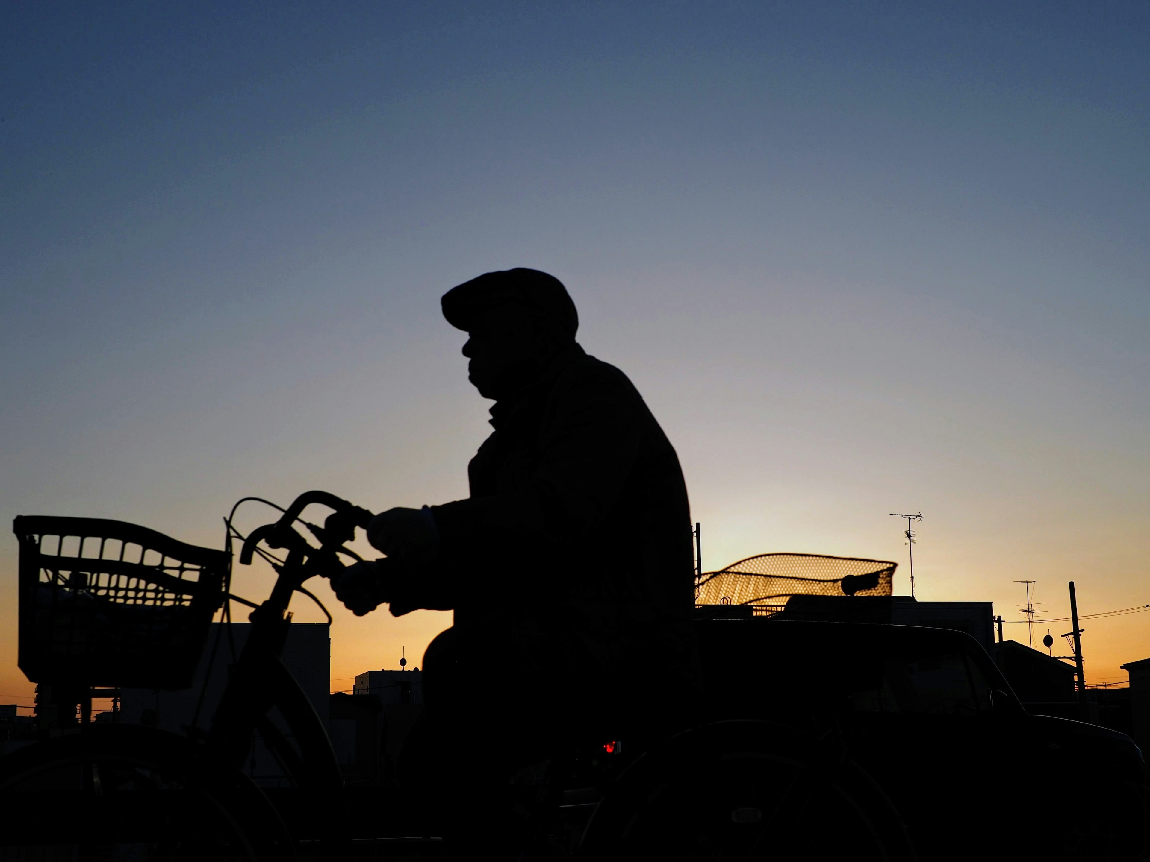 Silhouette of a man riding a bicycle against a sunset background