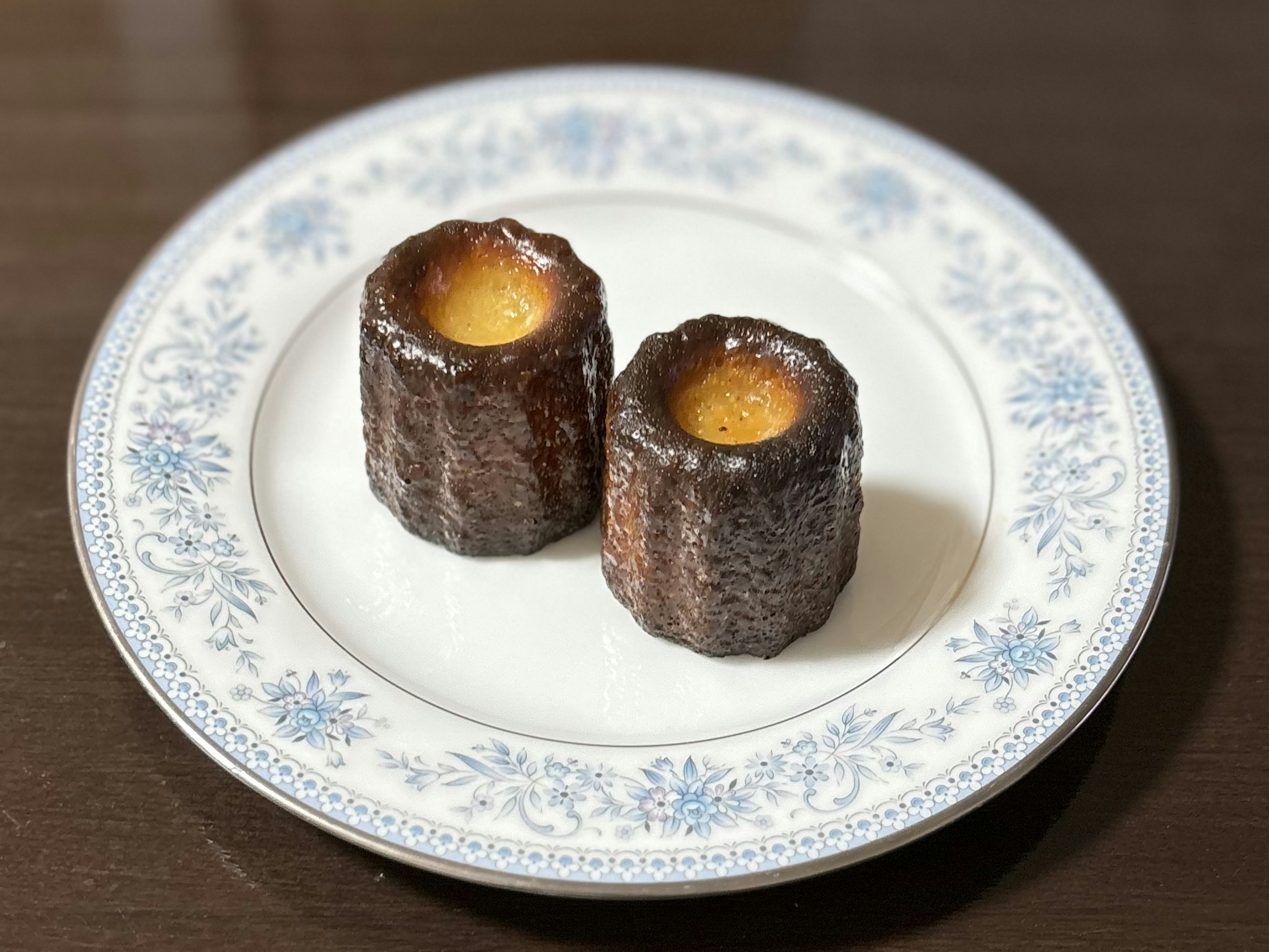 Deux canelés sur une assiette à fleurs blanches