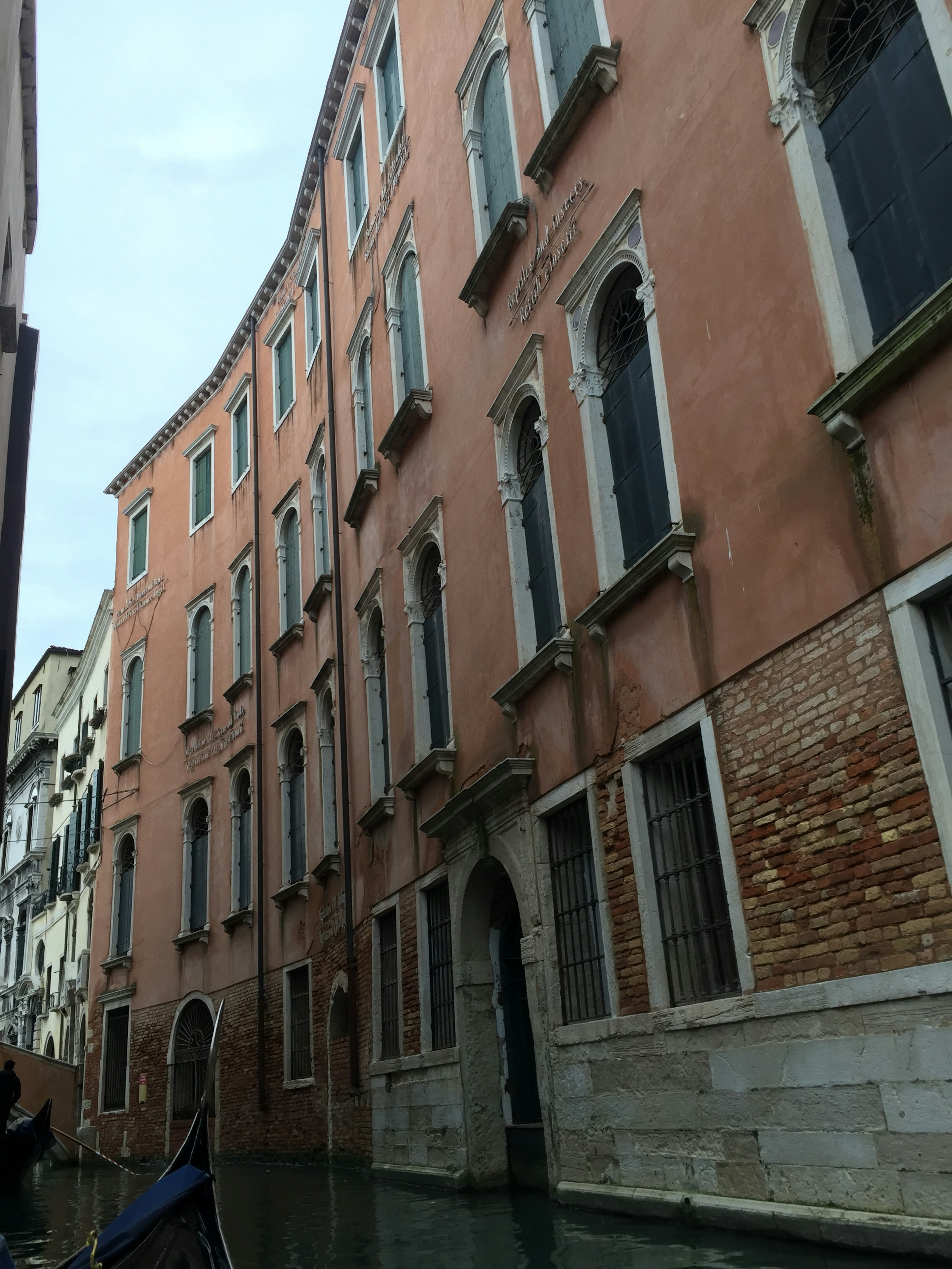 Una escena pintoresca de edificios rosas a lo largo de un canal en Venecia con ventanas únicas