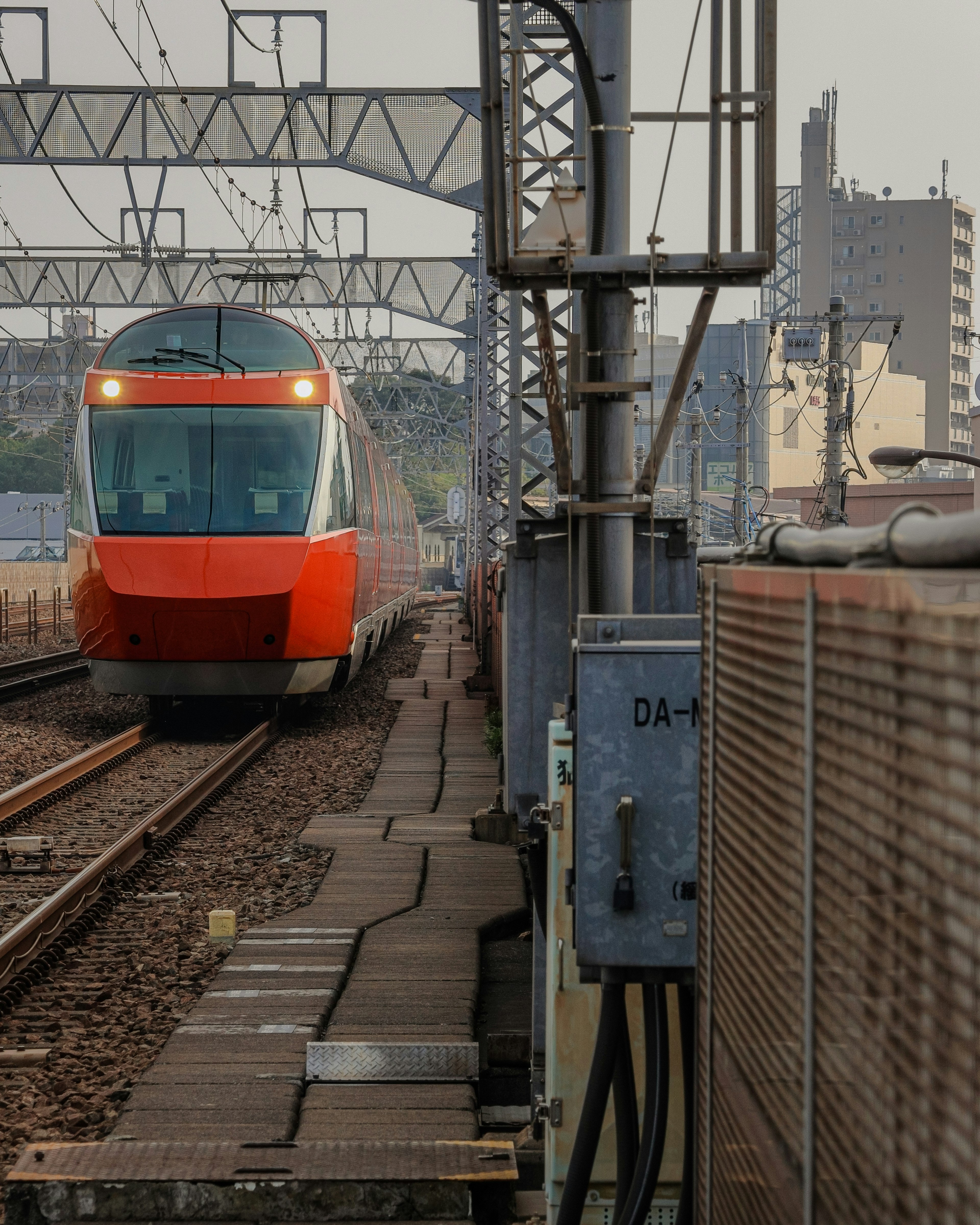 Red train approaching on railway tracks in an urban setting