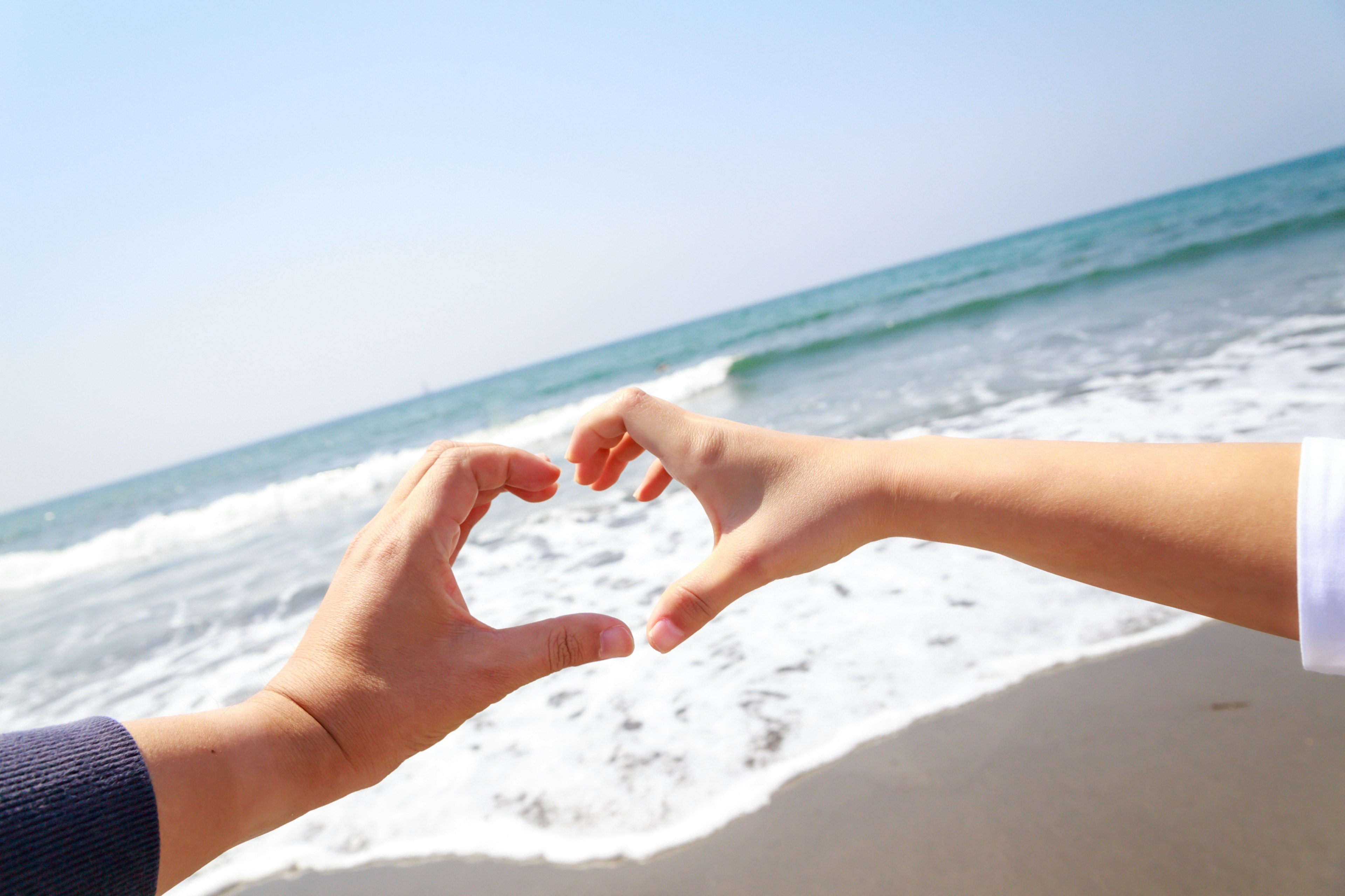 Due mani che formano un cuore sulla spiaggia