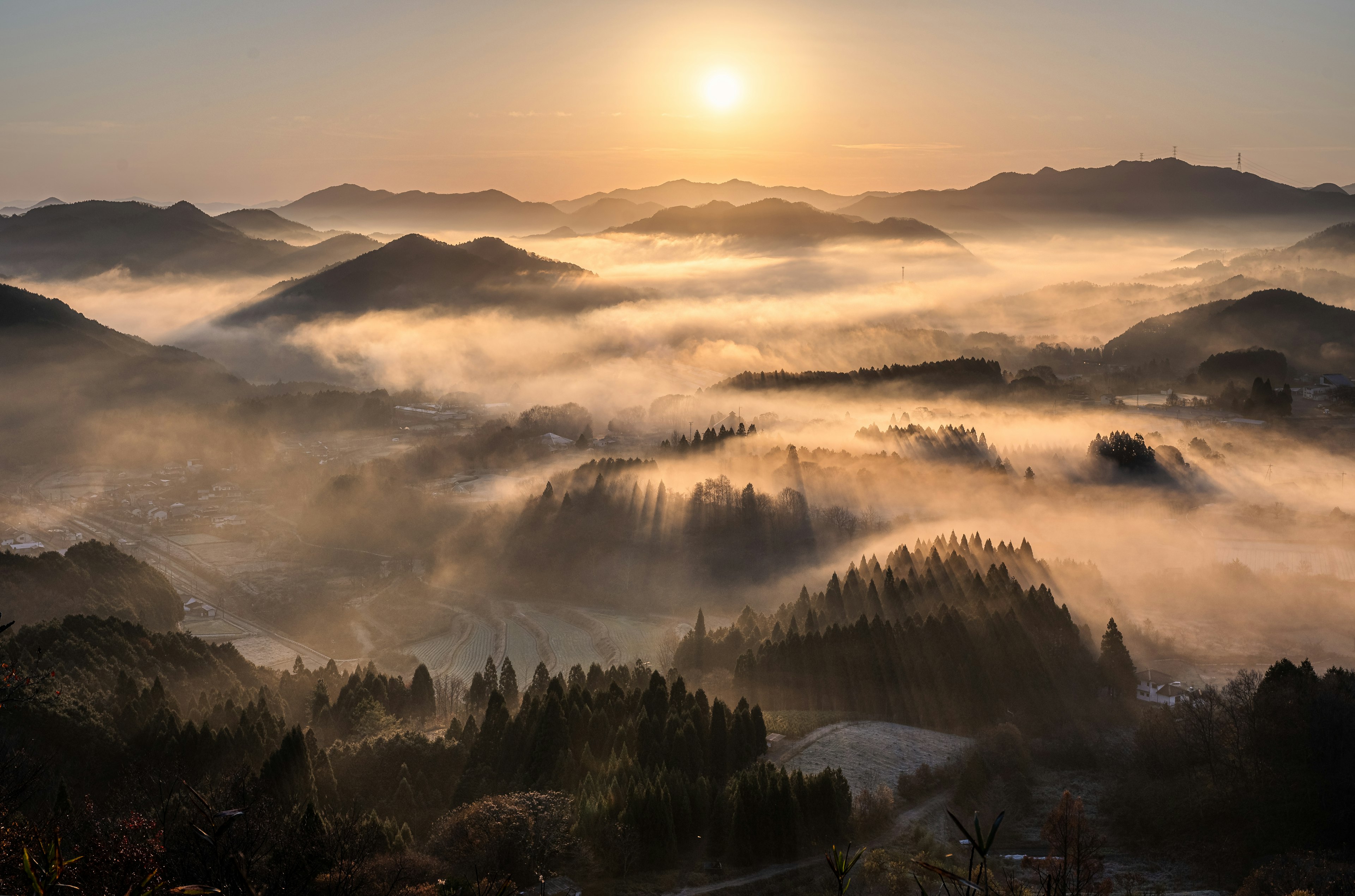 A landscape of misty mountains with a rising sun