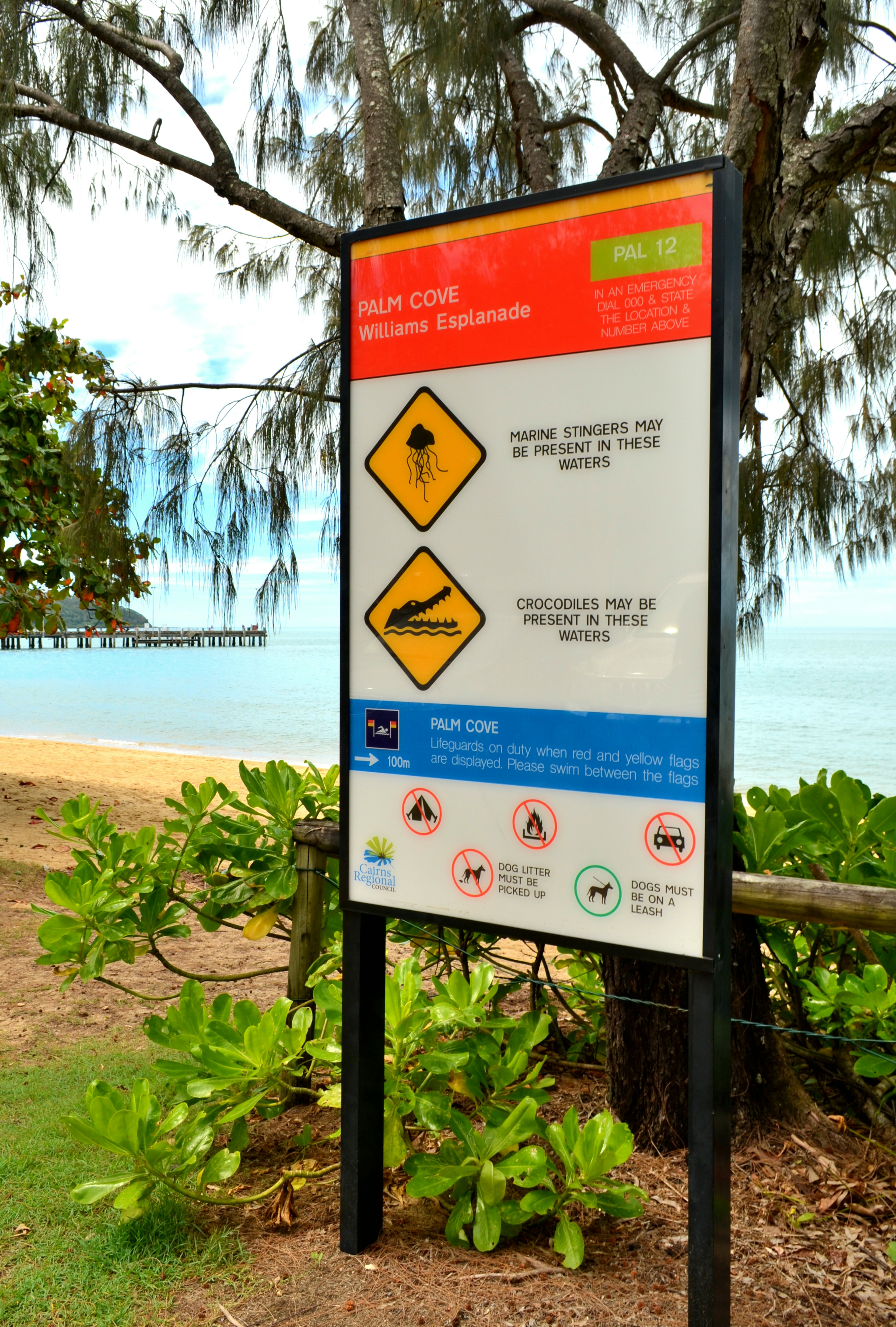 Coastal warning sign with surrounding lush greenery