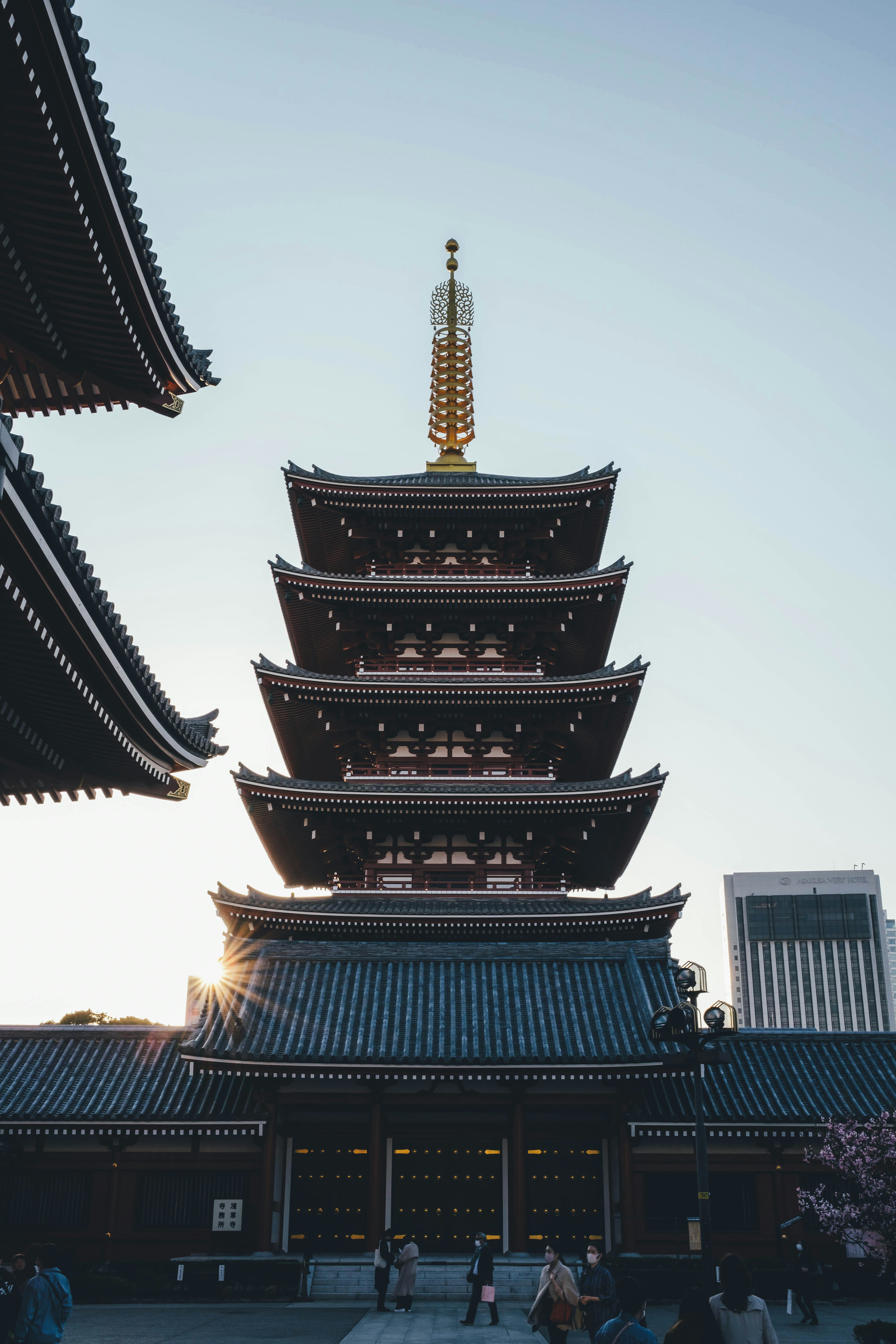 Five-story pagoda silhouetted against the sunset with surrounding buildings