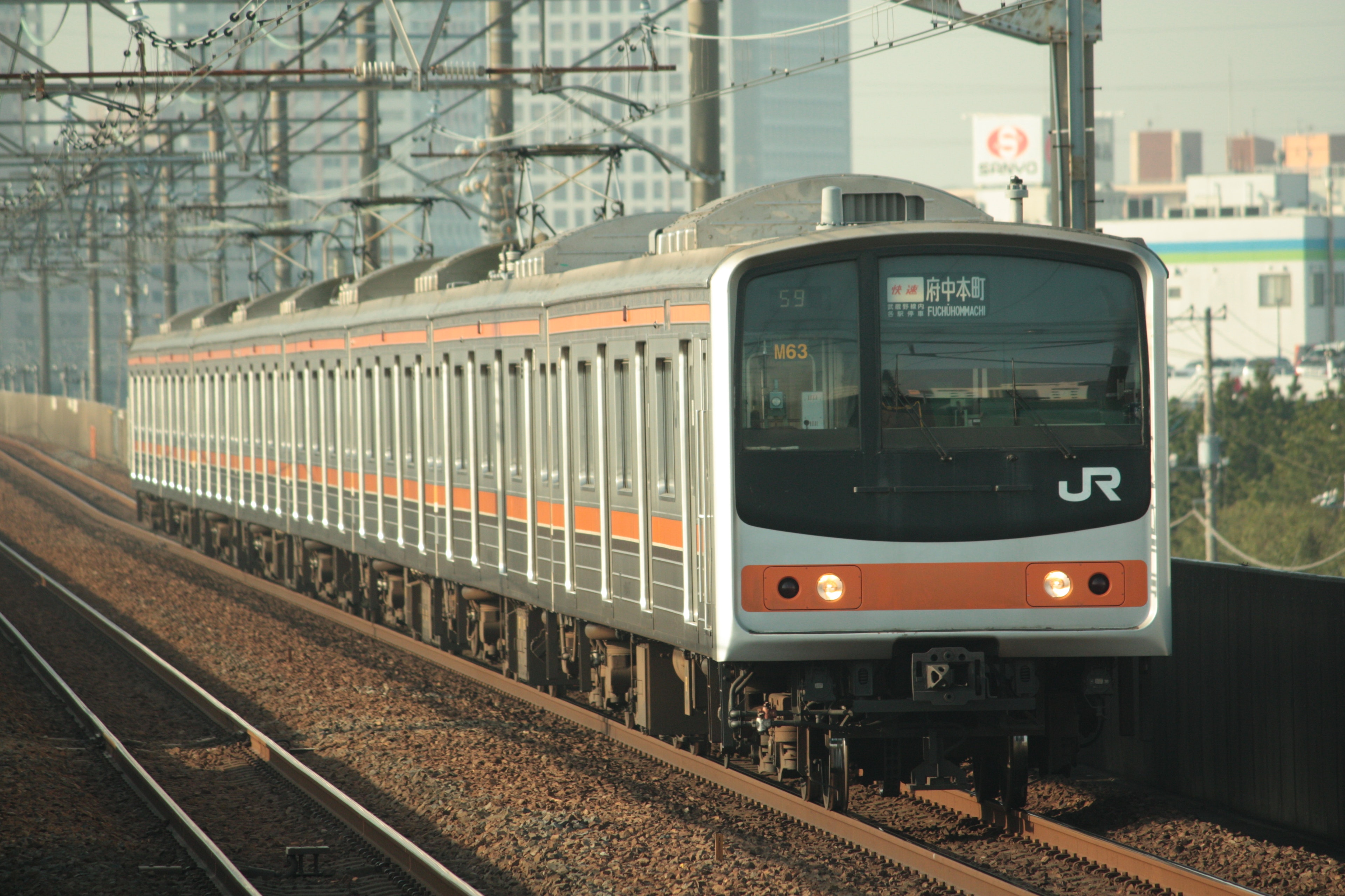 オレンジと白のJR電車が線路を走る風景