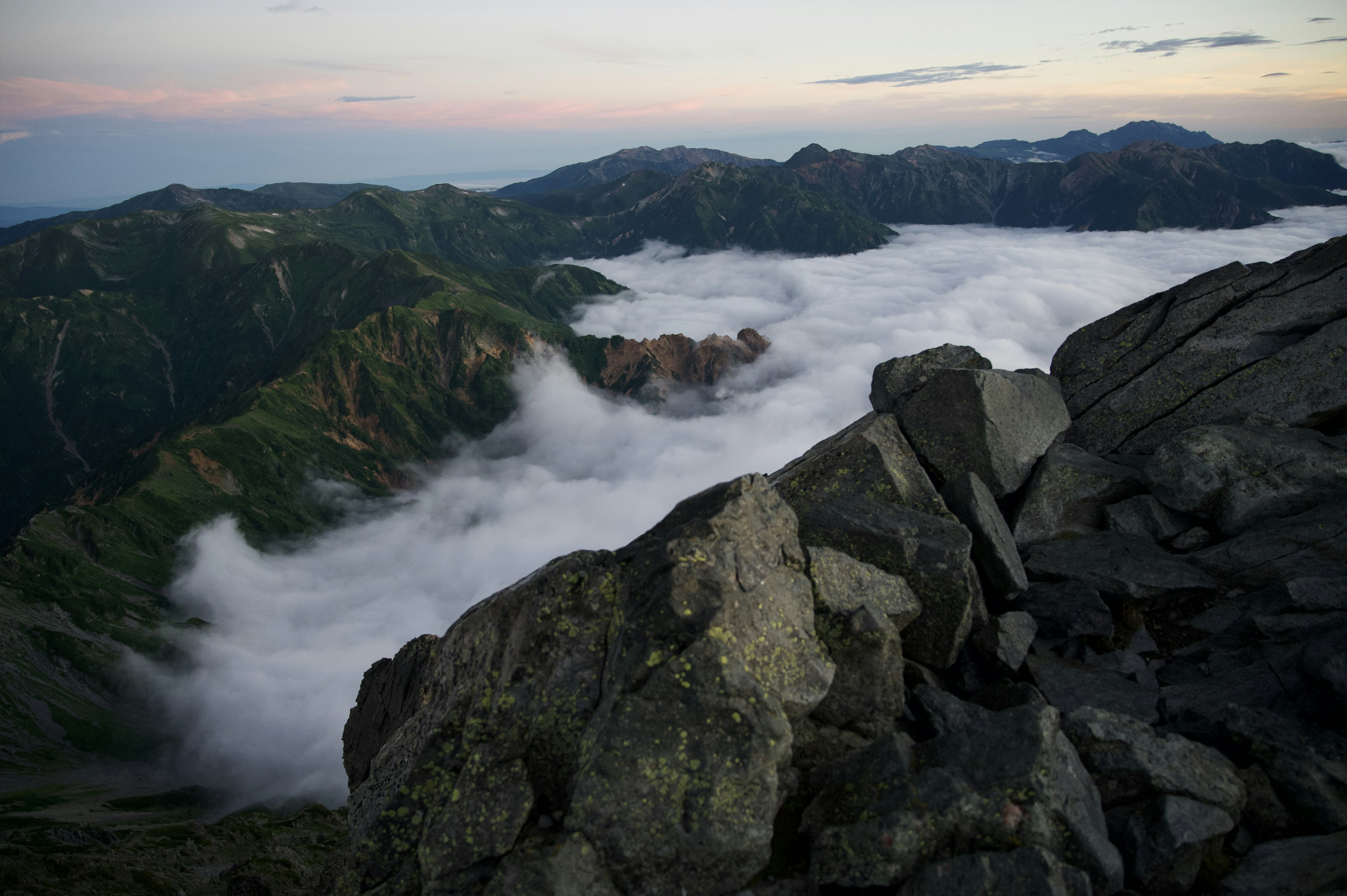 Vue panoramique depuis un sommet de montagne sur une mer de nuages et un terrain rocheux