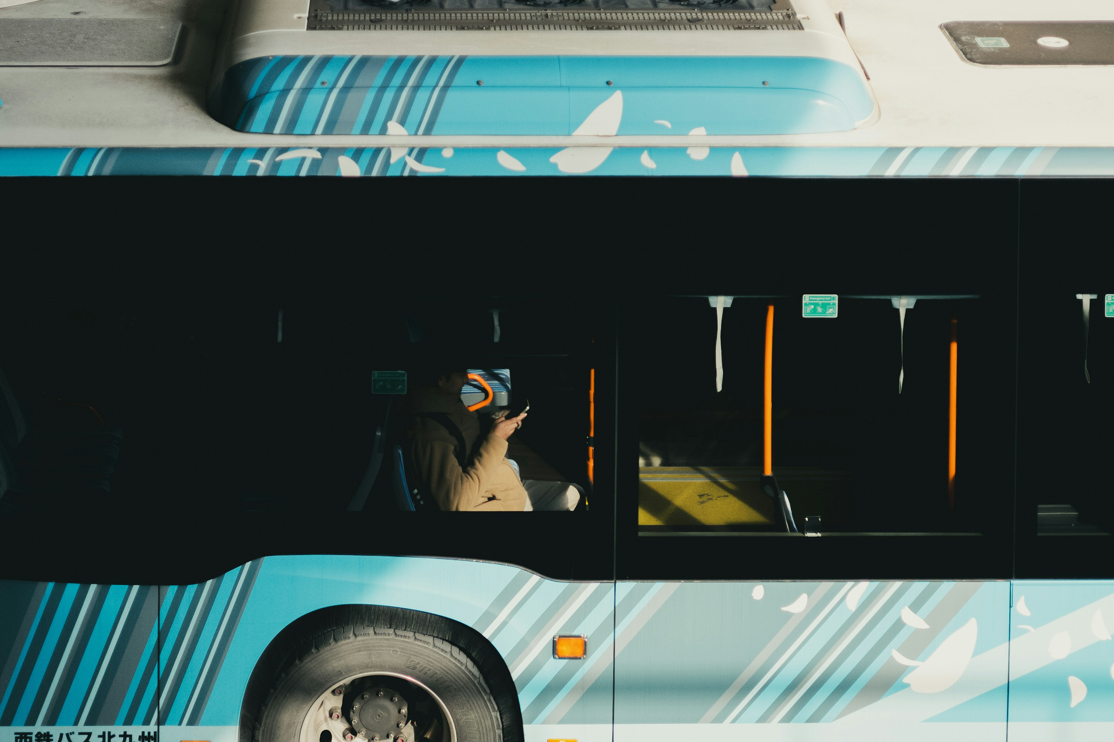 Una persona sosteniendo un teléfono dentro de un autobús azul con patrones artísticos