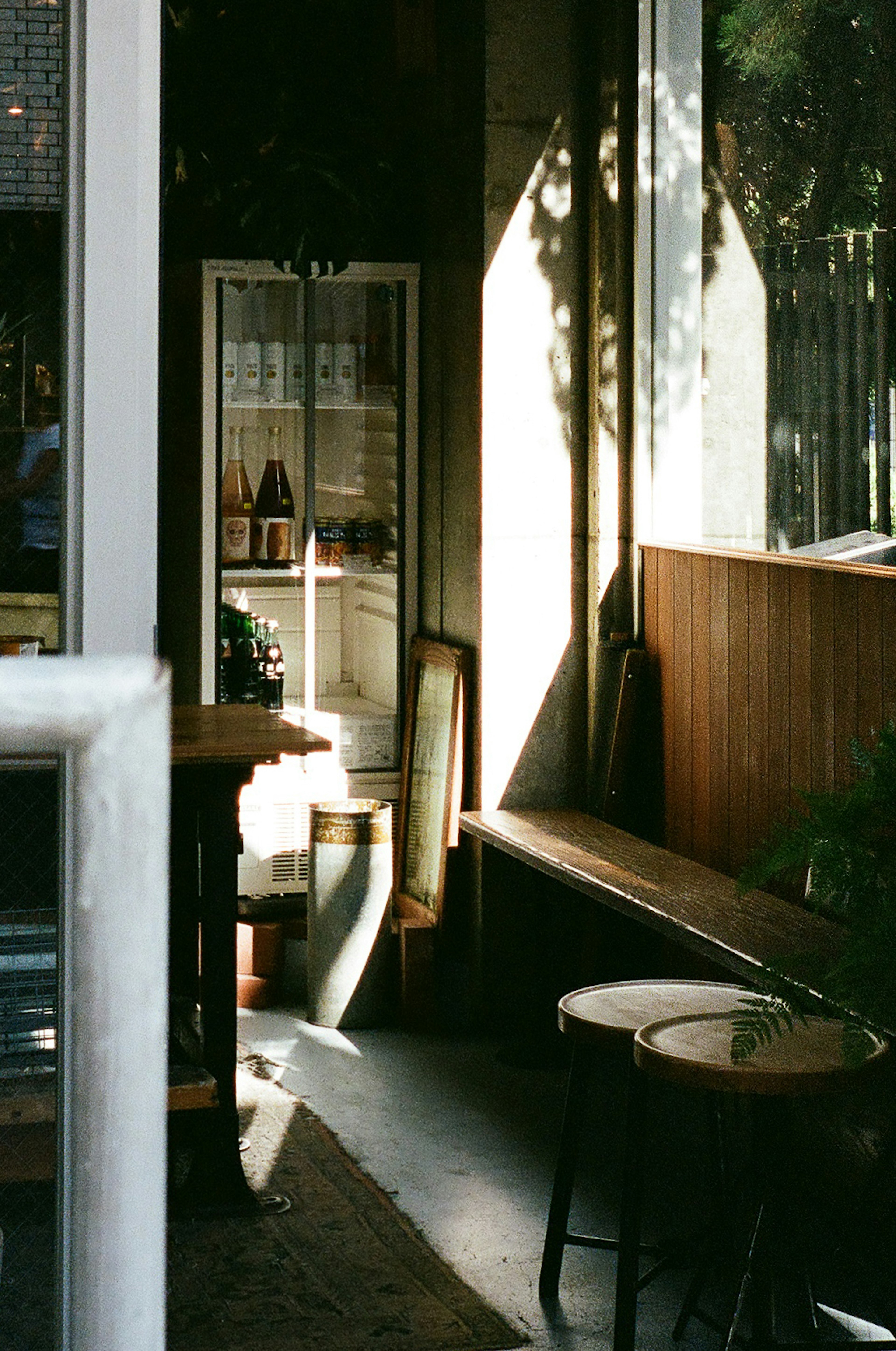 Ruhige Ecke eines Cafés mit Holzbänken und Tischen Sonnenlicht strömt durch das Fenster