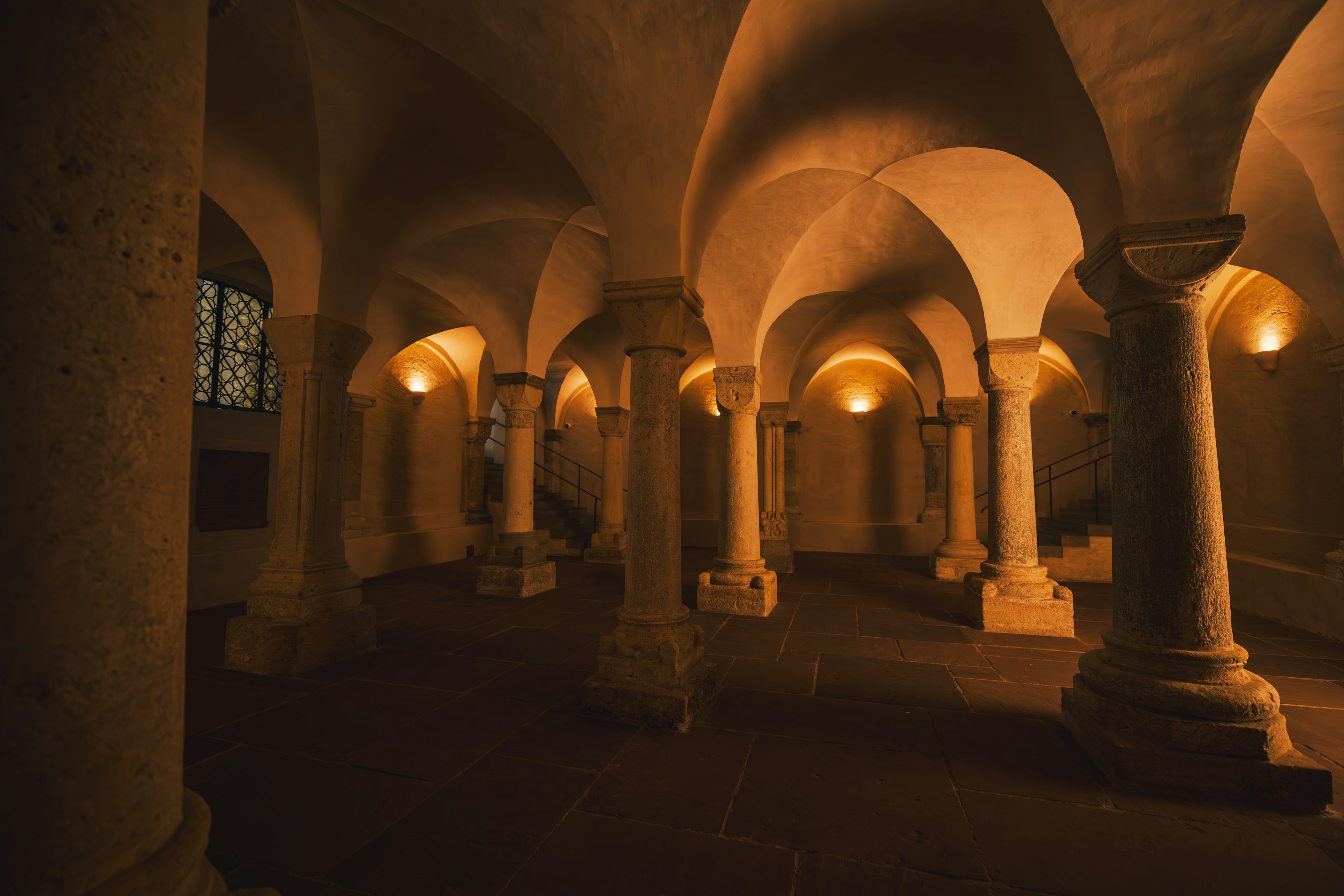 Intérieur d'un espace souterrain faiblement éclairé avec des colonnes arquées