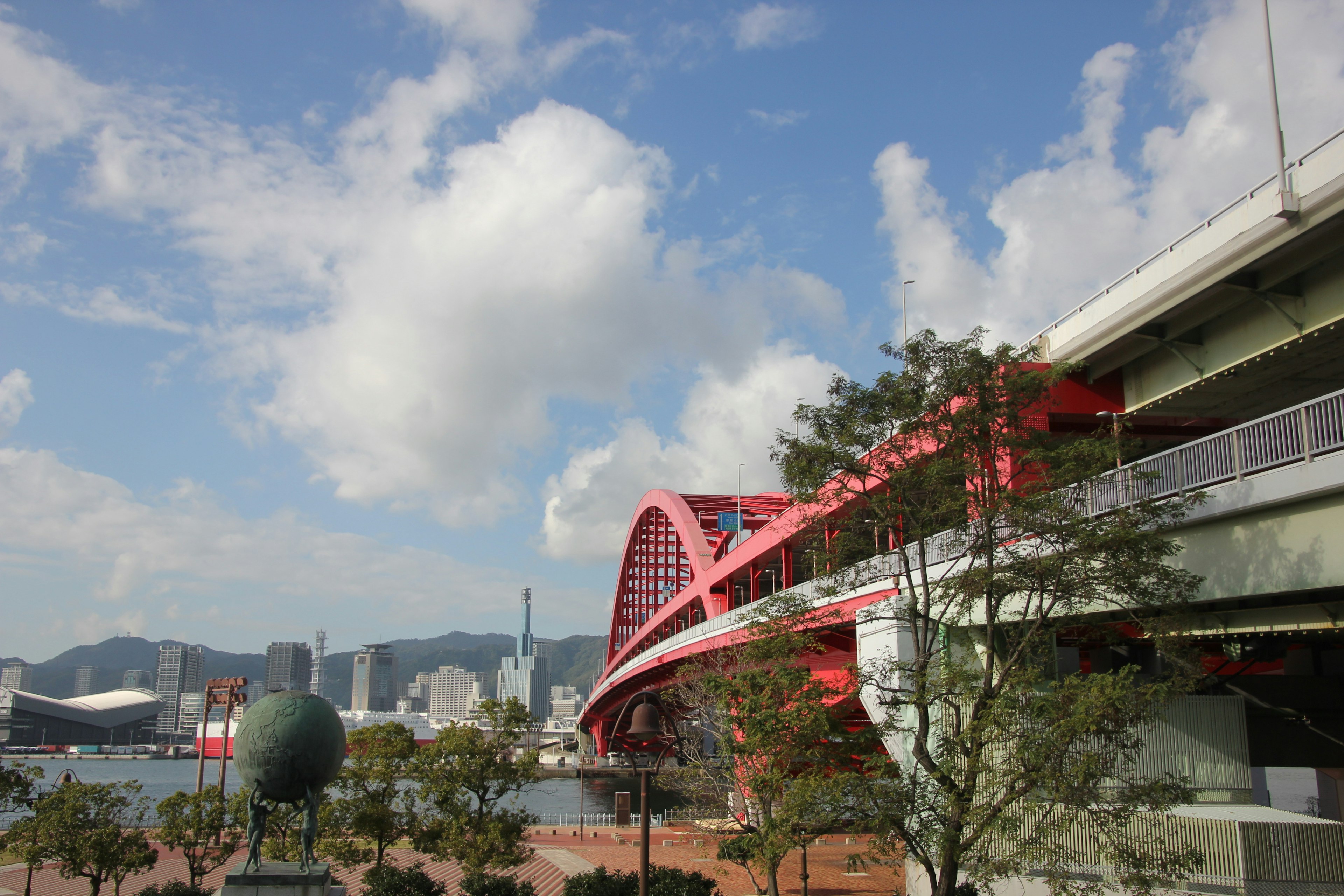 藍天下的紅色拱橋 港口旁的現代建築