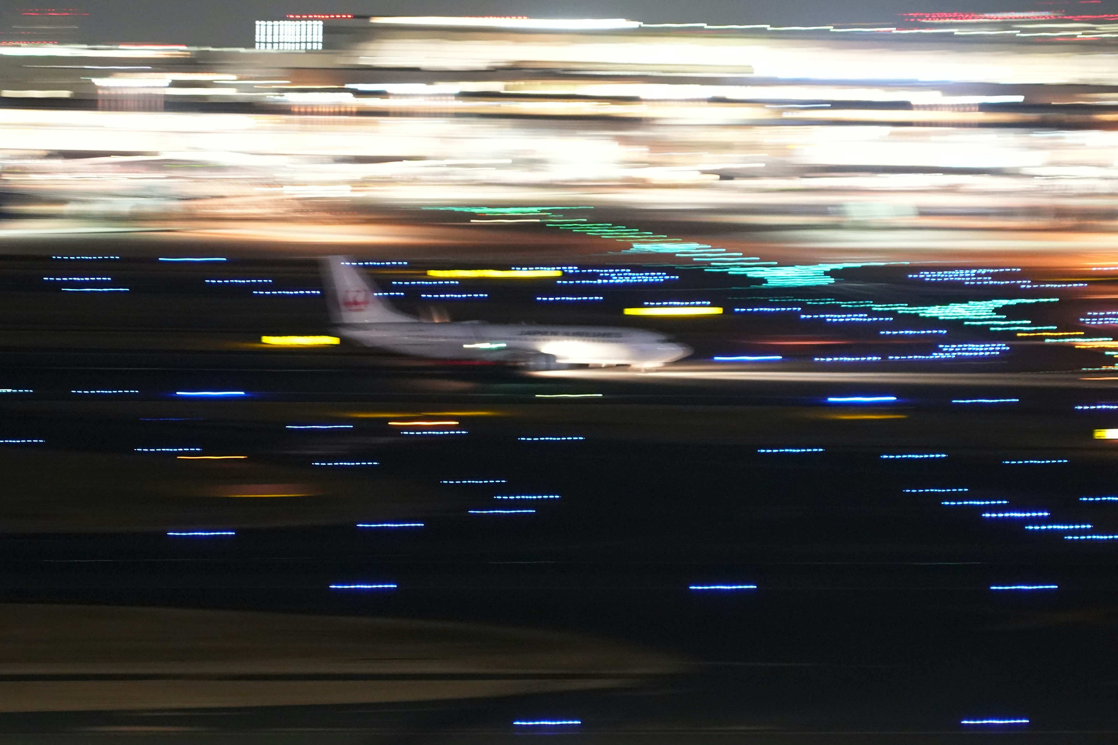 Airplane taking off at night with colorful runway lights