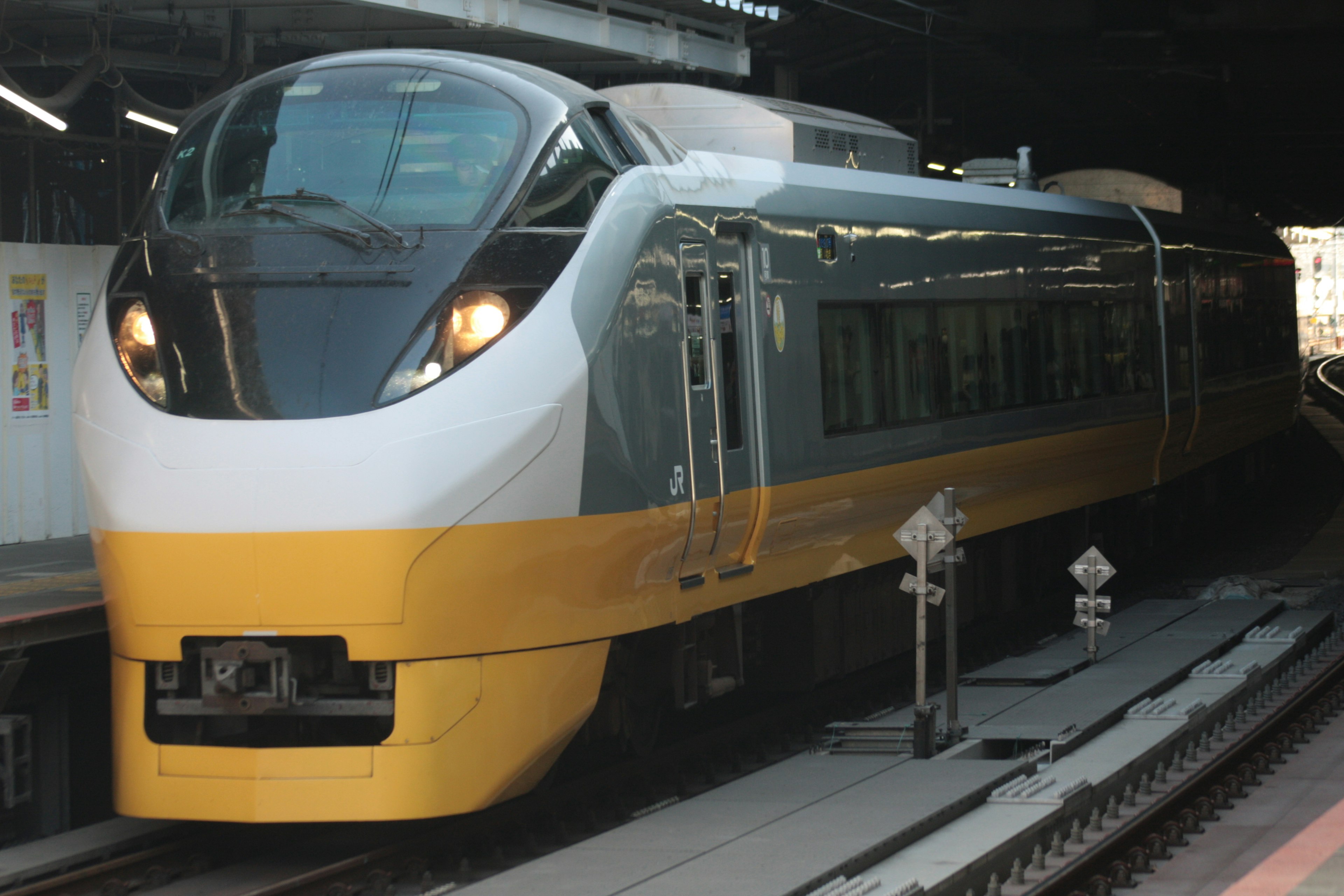 Kereta ekspres dengan desain kuning dan putih terparkir di stasiun