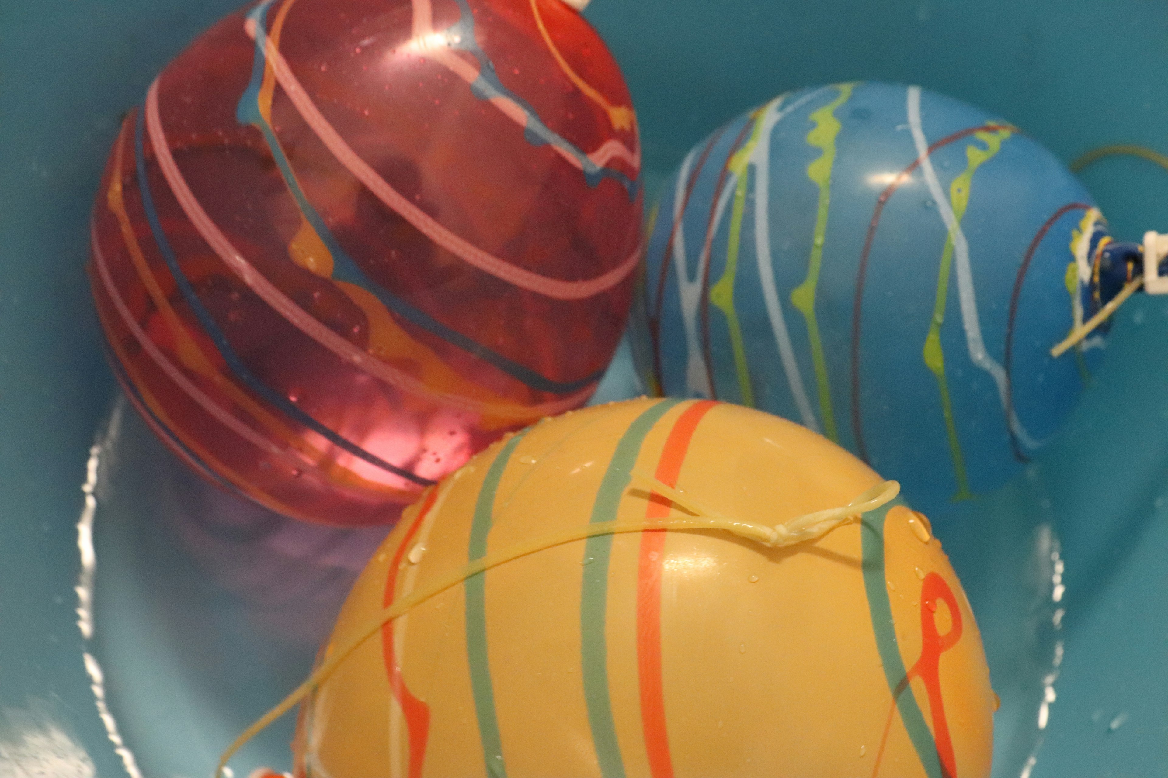 Three colorful decorated water balls floating in a blue bowl