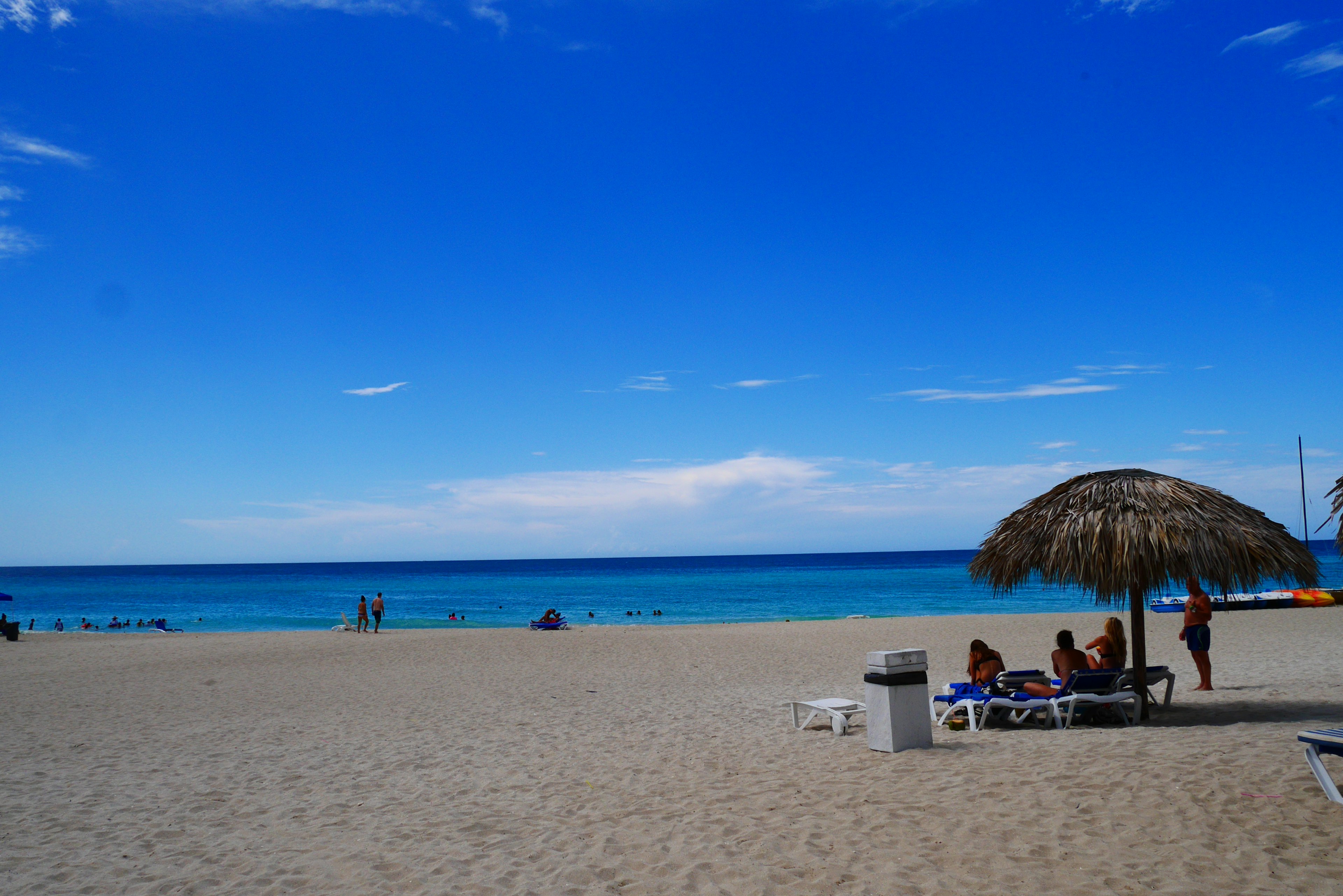 Strandszene mit blauem Himmel und Ozean Strohdach und Menschen im Sand