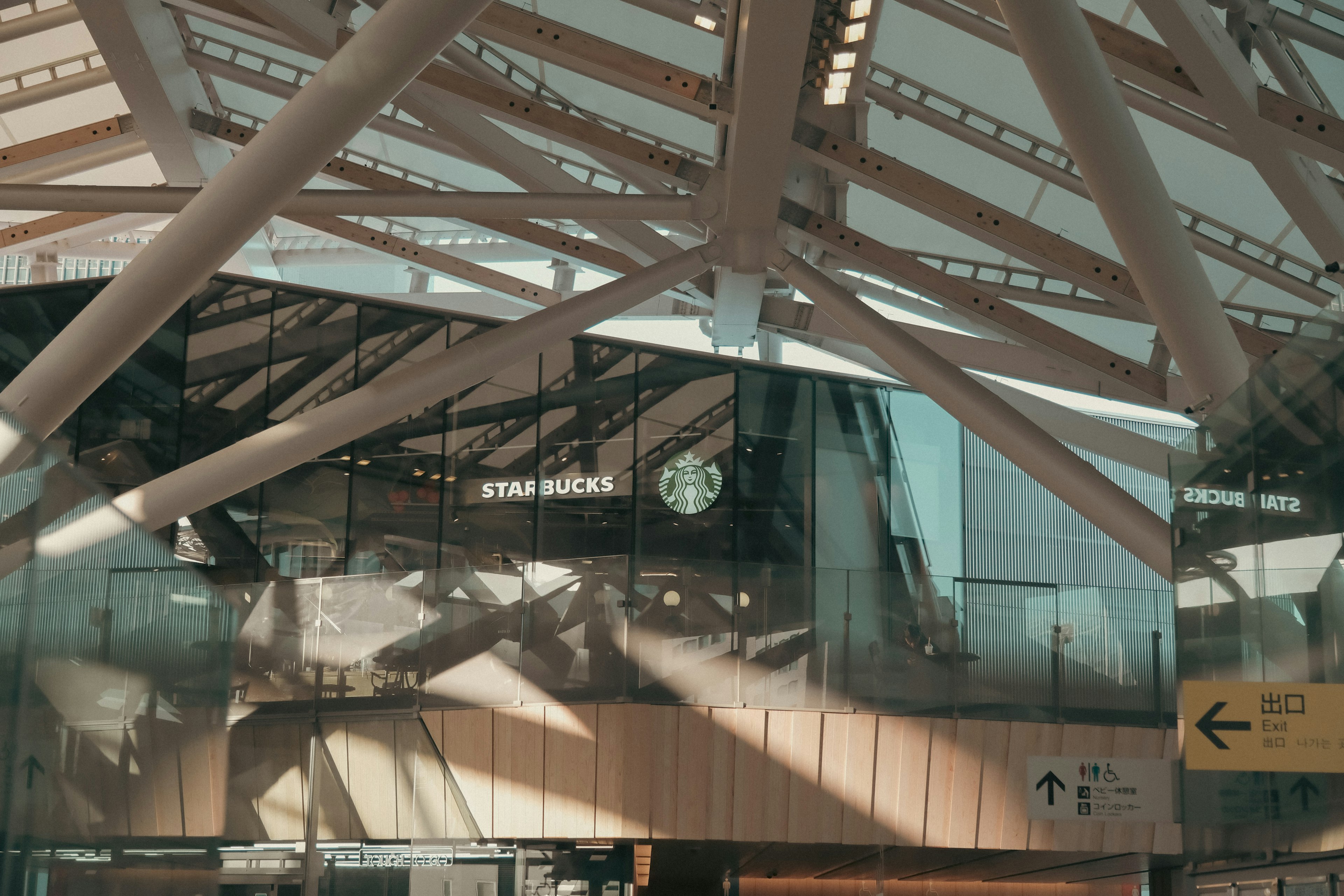 Vista interna di una stazione moderna che mostra travi strutturali e riflessi di vetro