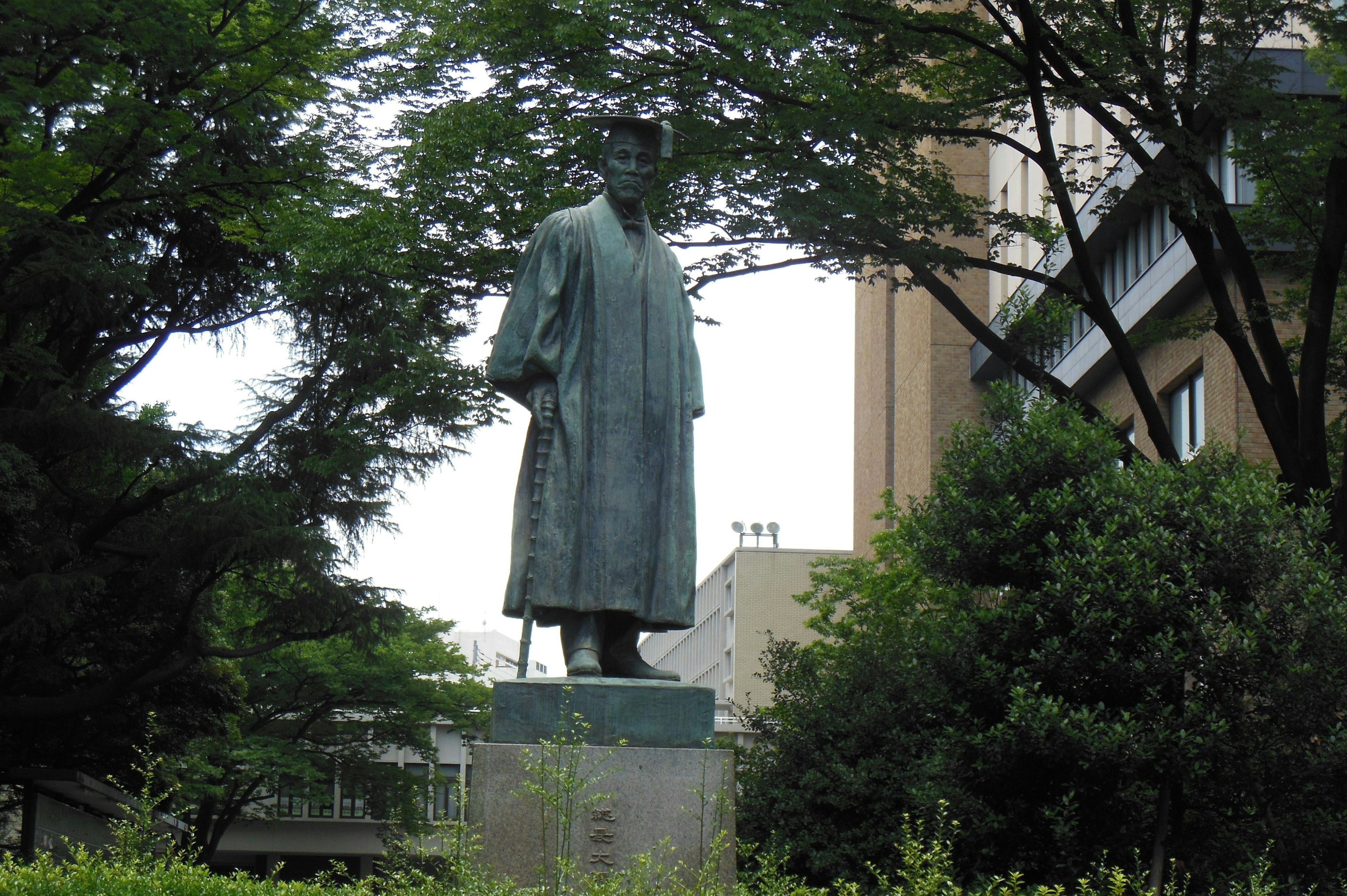 Bronzestatue, die in einem Park steht, umgeben von Grün, darstellt eine historische Figur