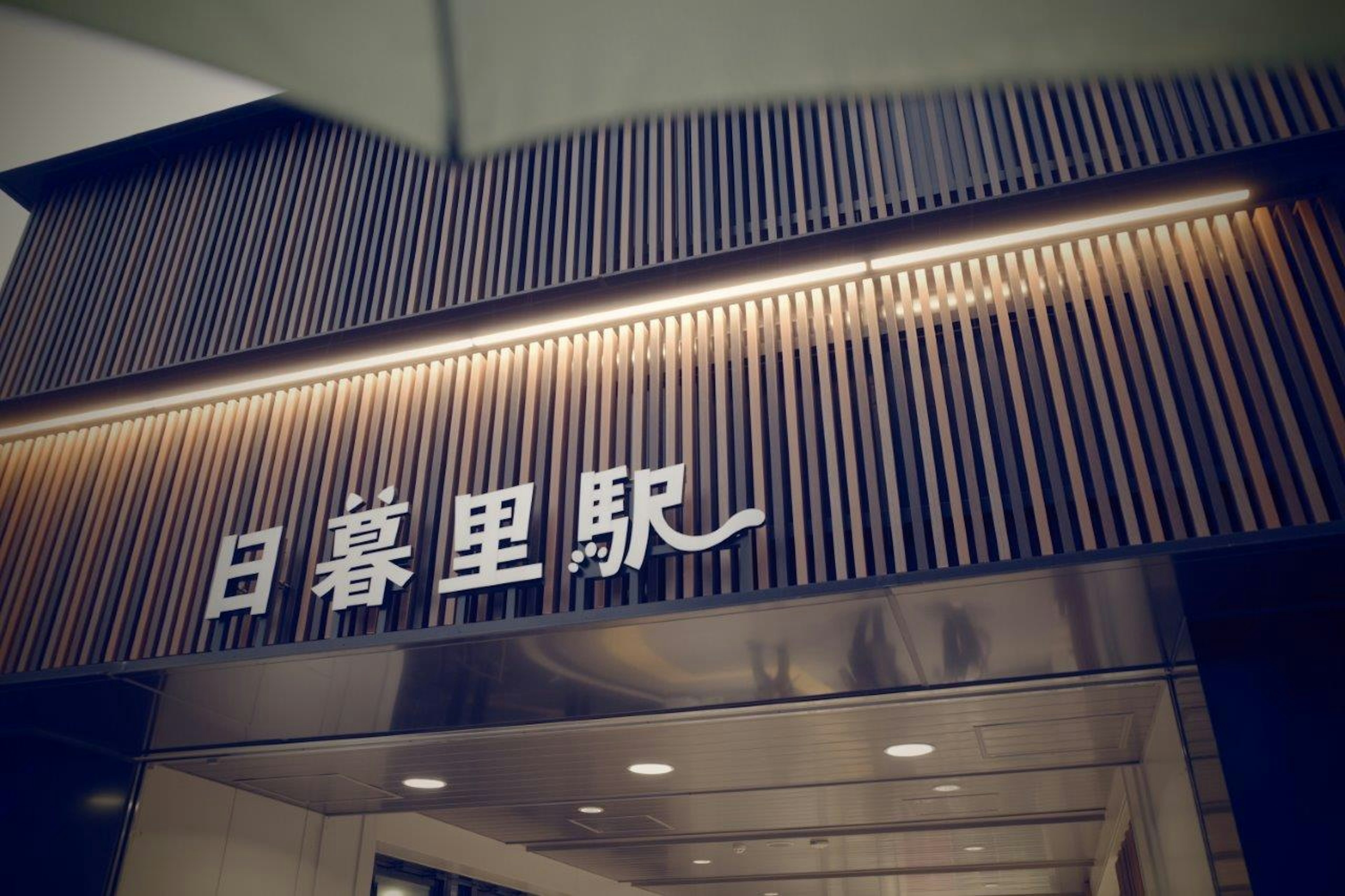 Sign of Nippori Station set against a wooden design background